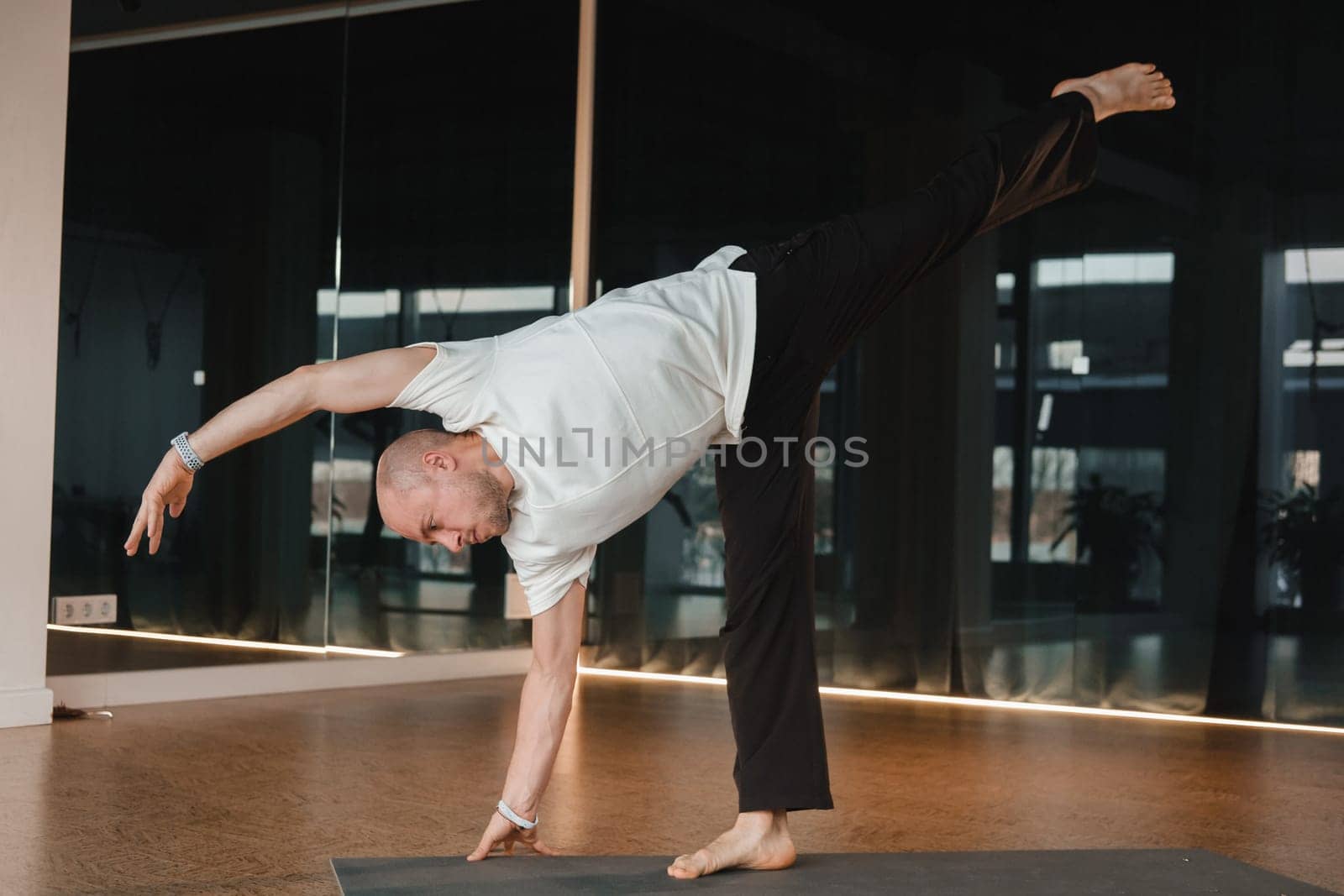 An athletic young man does exercises in the fitness room. A professional guy does yoga in the gym.