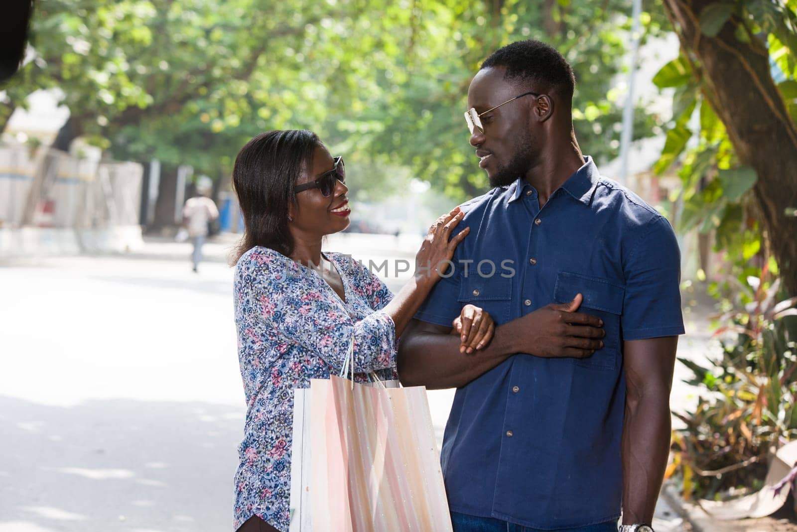 young woman standing outdoors cuddling her boyfriend smiling after shopping.