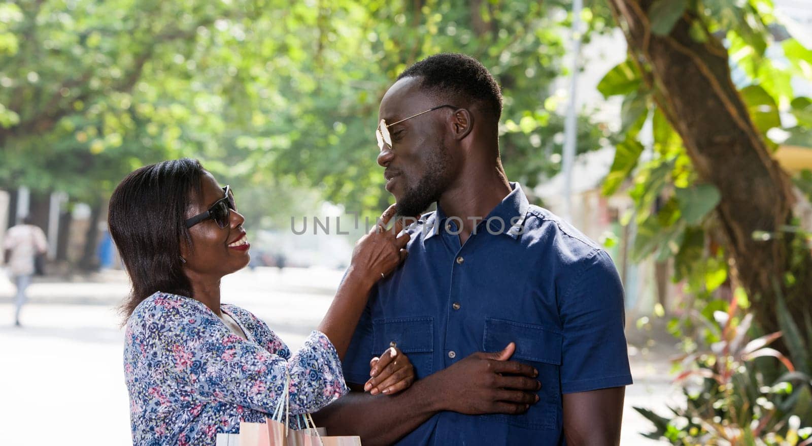 young woman standing outdoors cuddling her boyfriend smiling after shopping.