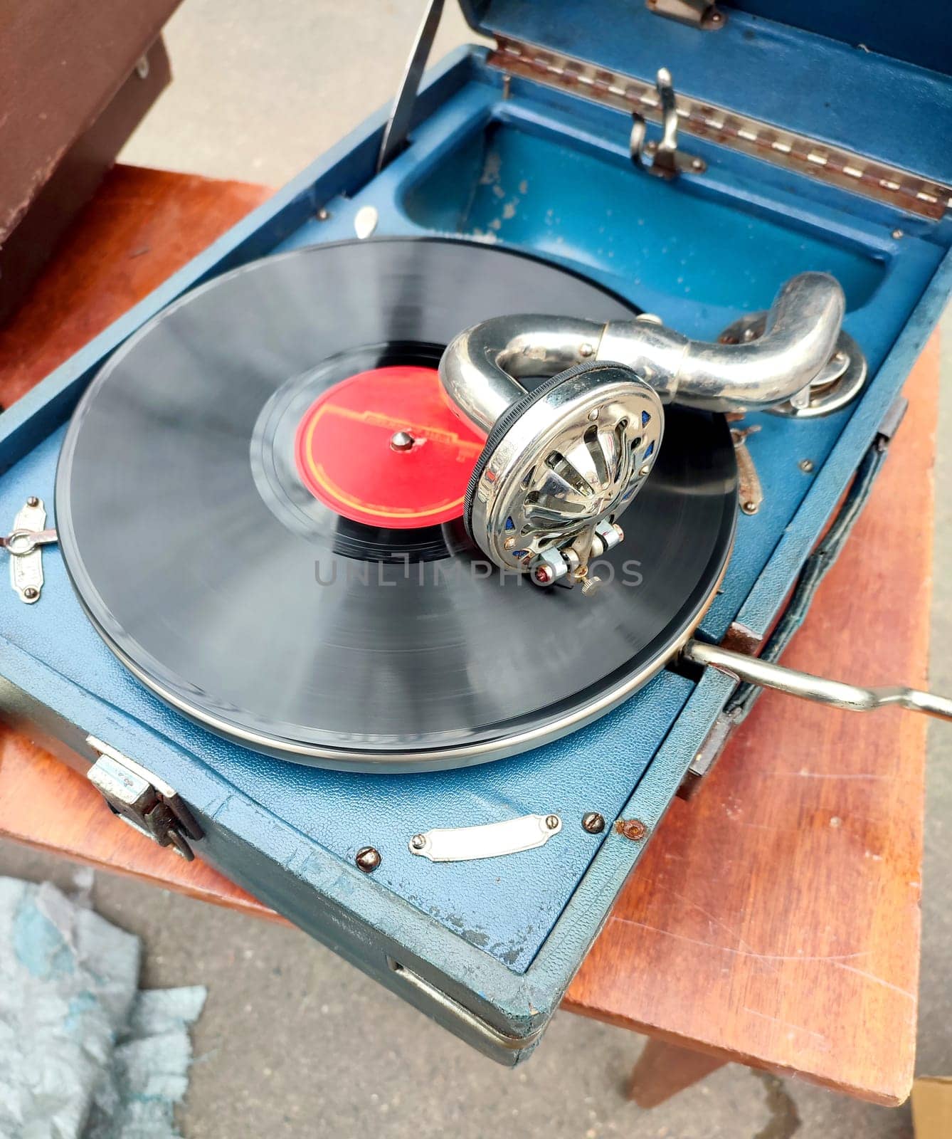 An old retro record playing on old vintage gramophone at flea market. Work of portable gramophone. Old vintage shabby record player, phonograph, potefone. Needle. Nostalgia antique audio turntable