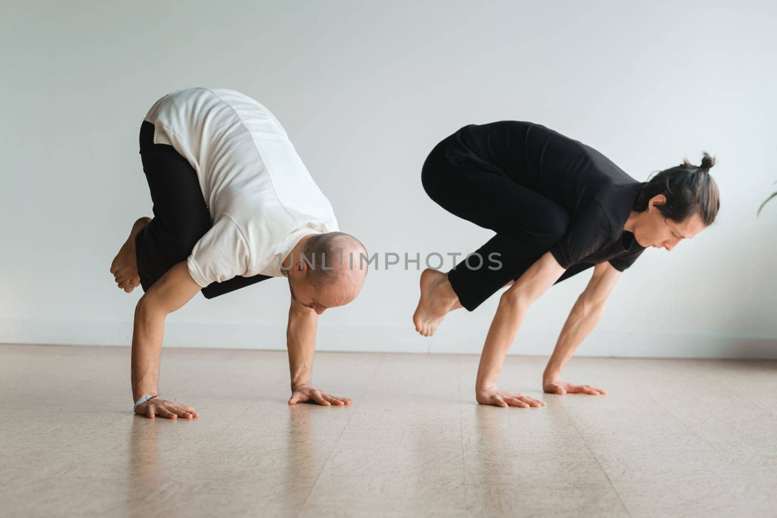 two young athletes practice yoga in the gym. Joint training, indoors, studio. The concept of a healthy lifestyle by Lobachad