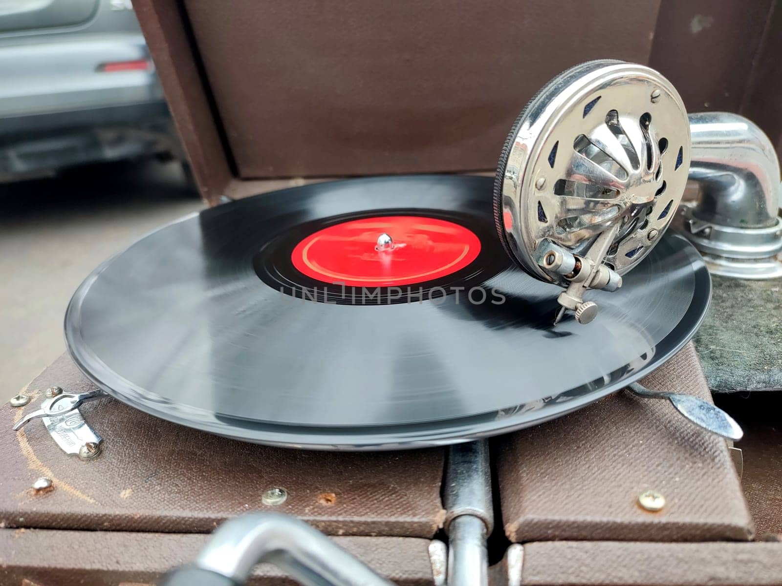 An old retro record playing on old vintage gramophone at flea market. Work of portable gramophone. Old vintage shabby record player, phonograph, potefone. Needle close up. Nostalgia antique turntable