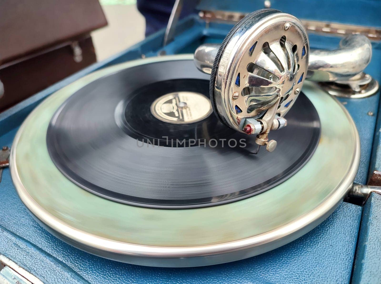 An old retro record playing on old vintage gramophone at flea market. Work of portable gramophone. Old vintage shabby record player, phonograph, potefone. Needle close up. Nostalgia antique turntable