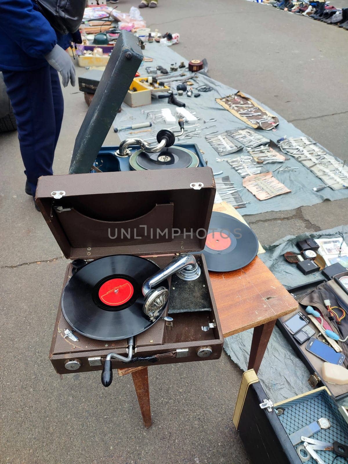 An old retro record playing on old vintage gramophone at flea market. Work of portable gramophone. Old vintage shabby record player, phonograph, potefone. Needle. Nostalgia antique audio turntable