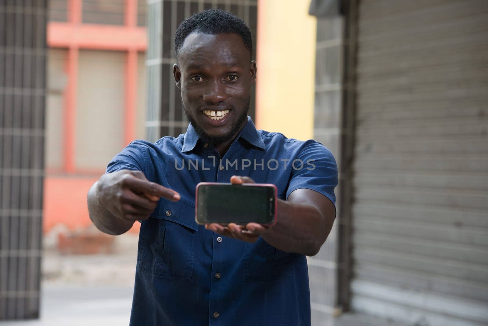 excited man expressing surprise on face and gesturing pointing at phone screen standing outside