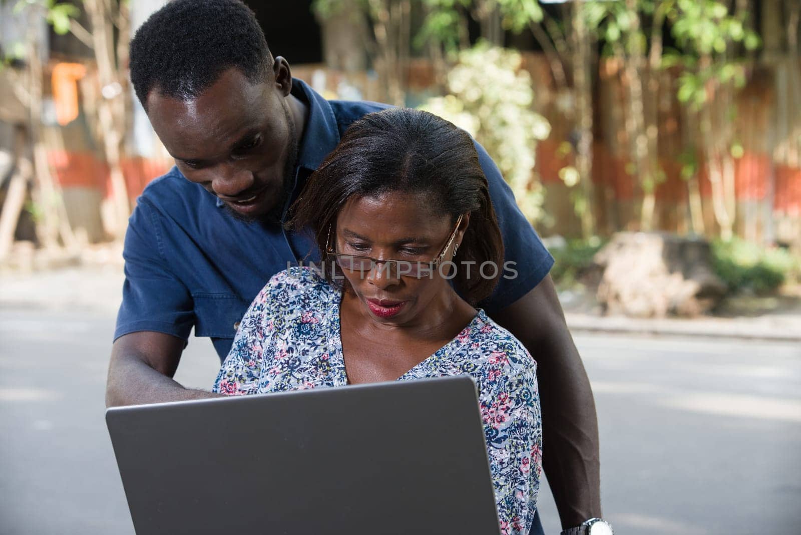 young couple sitting outside doing research with laptop.