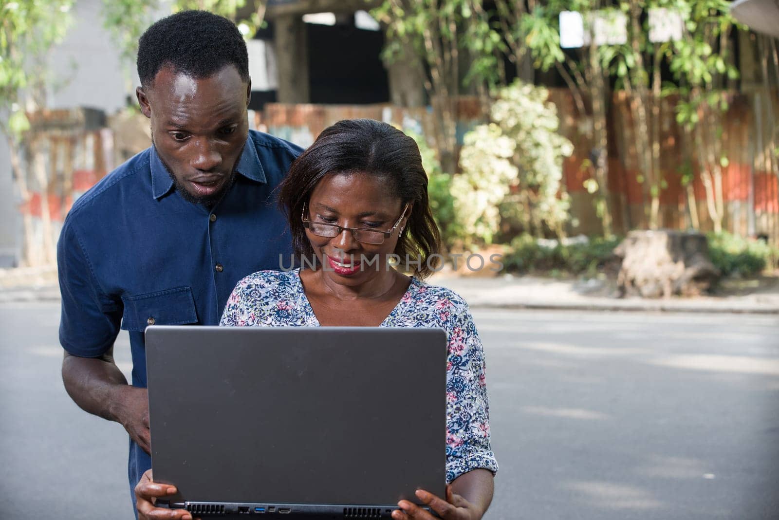 young couple outdoors looking at laptop smiling.