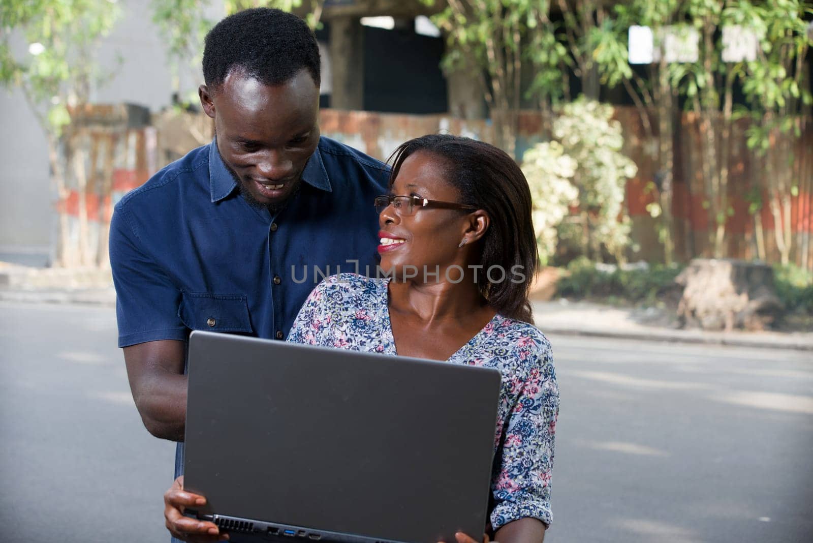 young woman sitting with laptop watching her boyfriend while he looks at the laptop smiling.