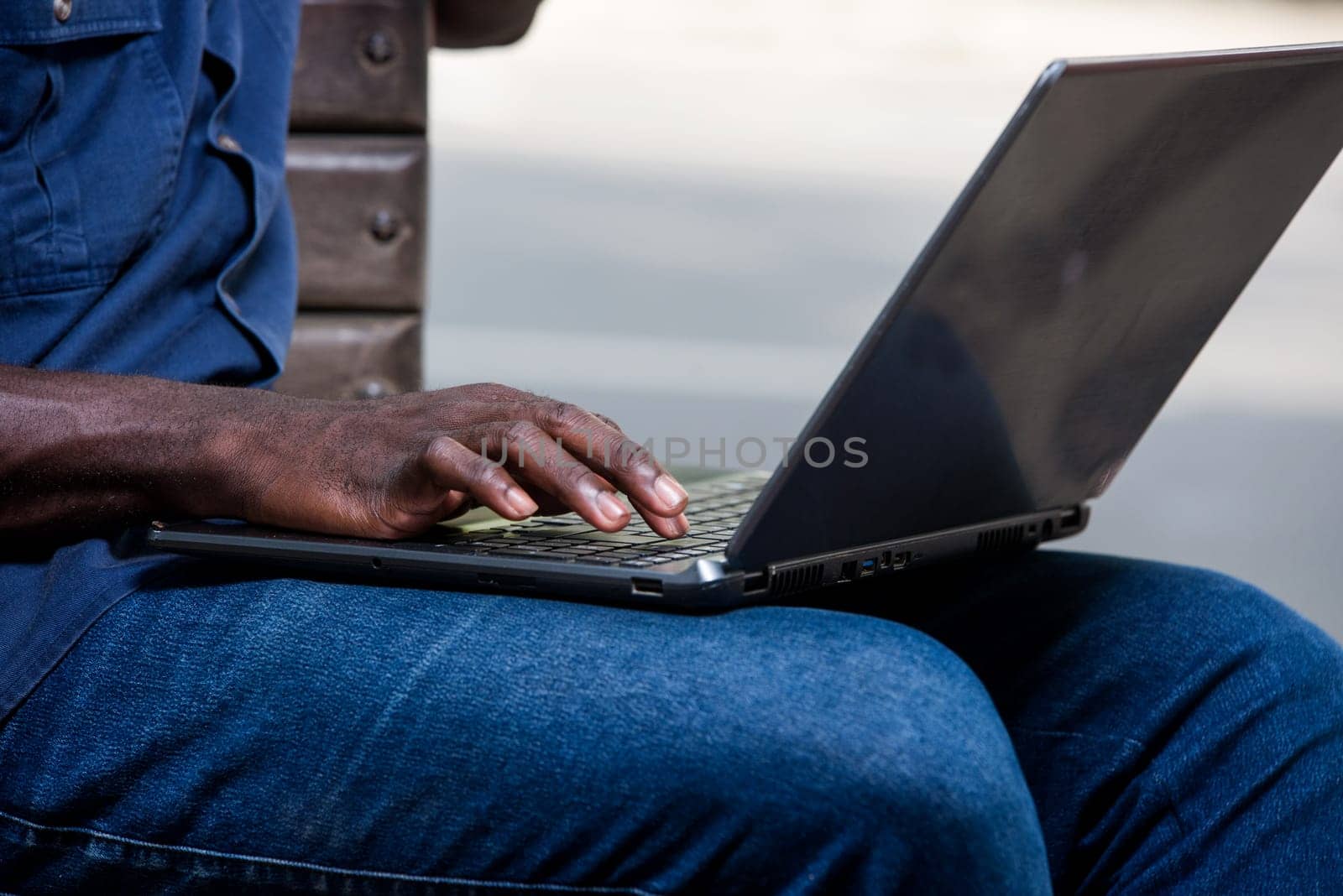 young man sitting outdoors doing research with laptop.