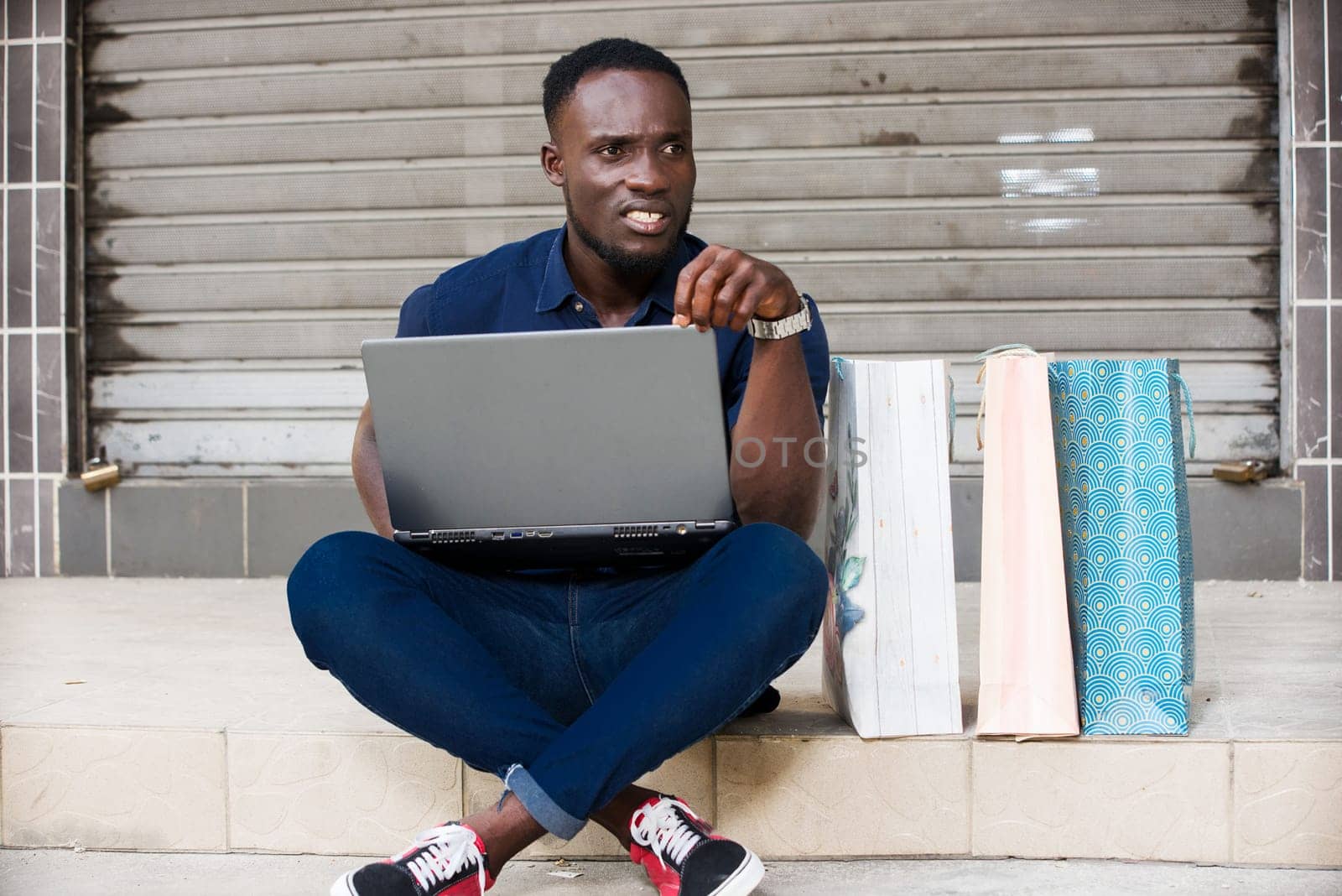 young man sitting on the floor with laptop after shopping thinking.