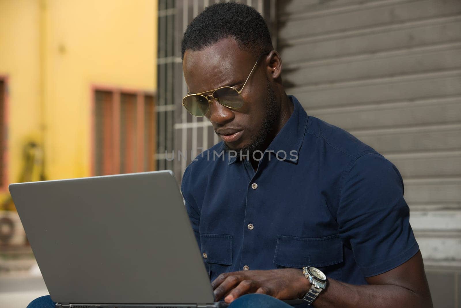 young man sitting outside looking at laptop.