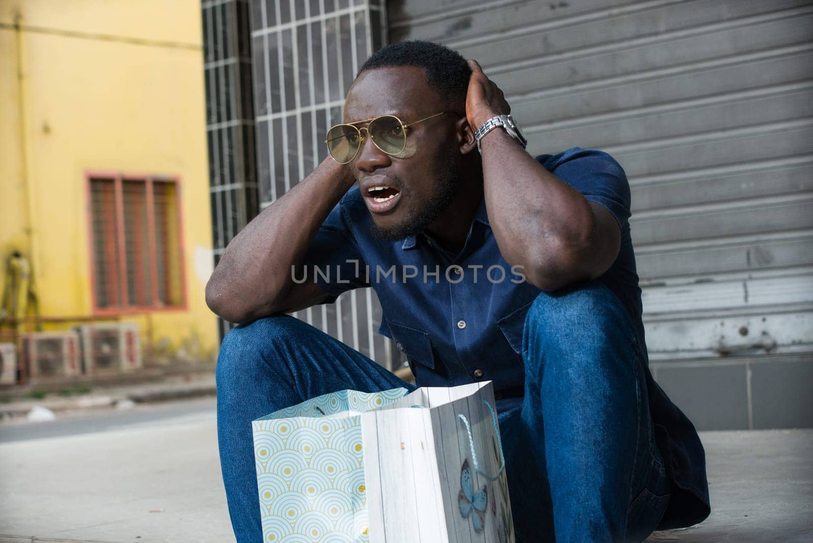 young man sitting on the floor thinking after shopping.