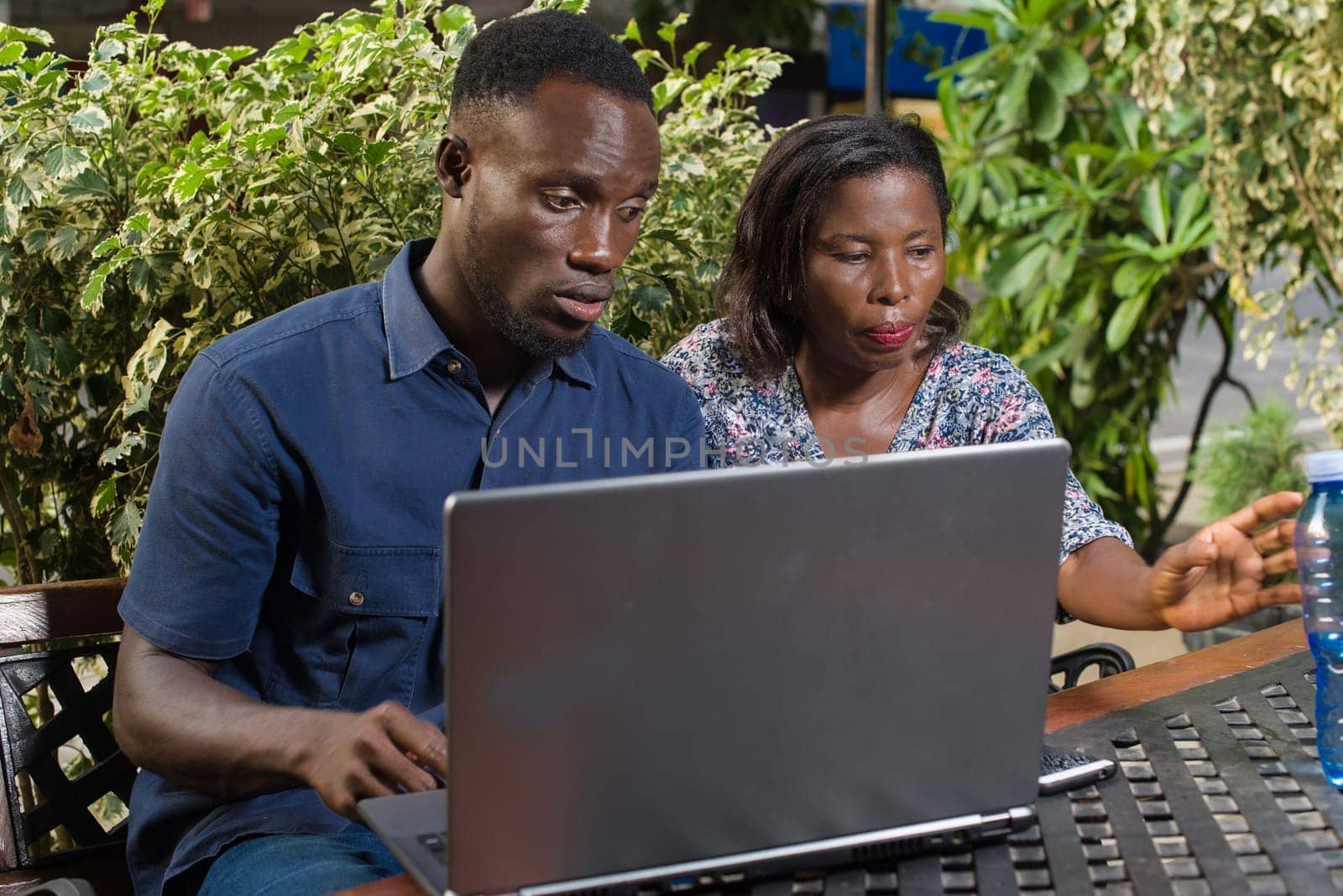 young couple sitting in a park watching laptop.