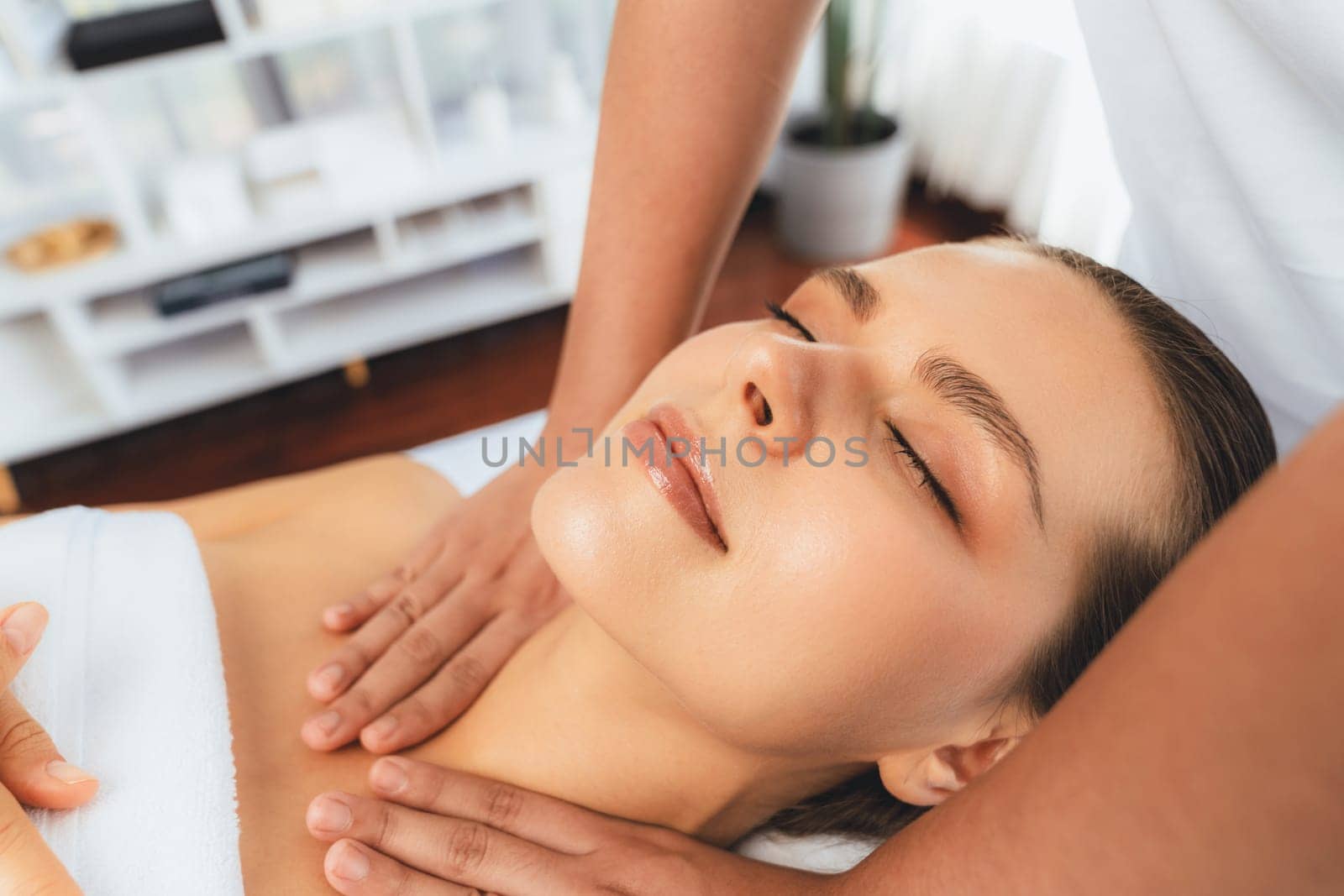 Caucasian woman customer enjoying relaxing anti-stress spa massage and pampering with beauty skin recreation leisure in day light ambient salon spa at luxury resort or hotel. Quiescent