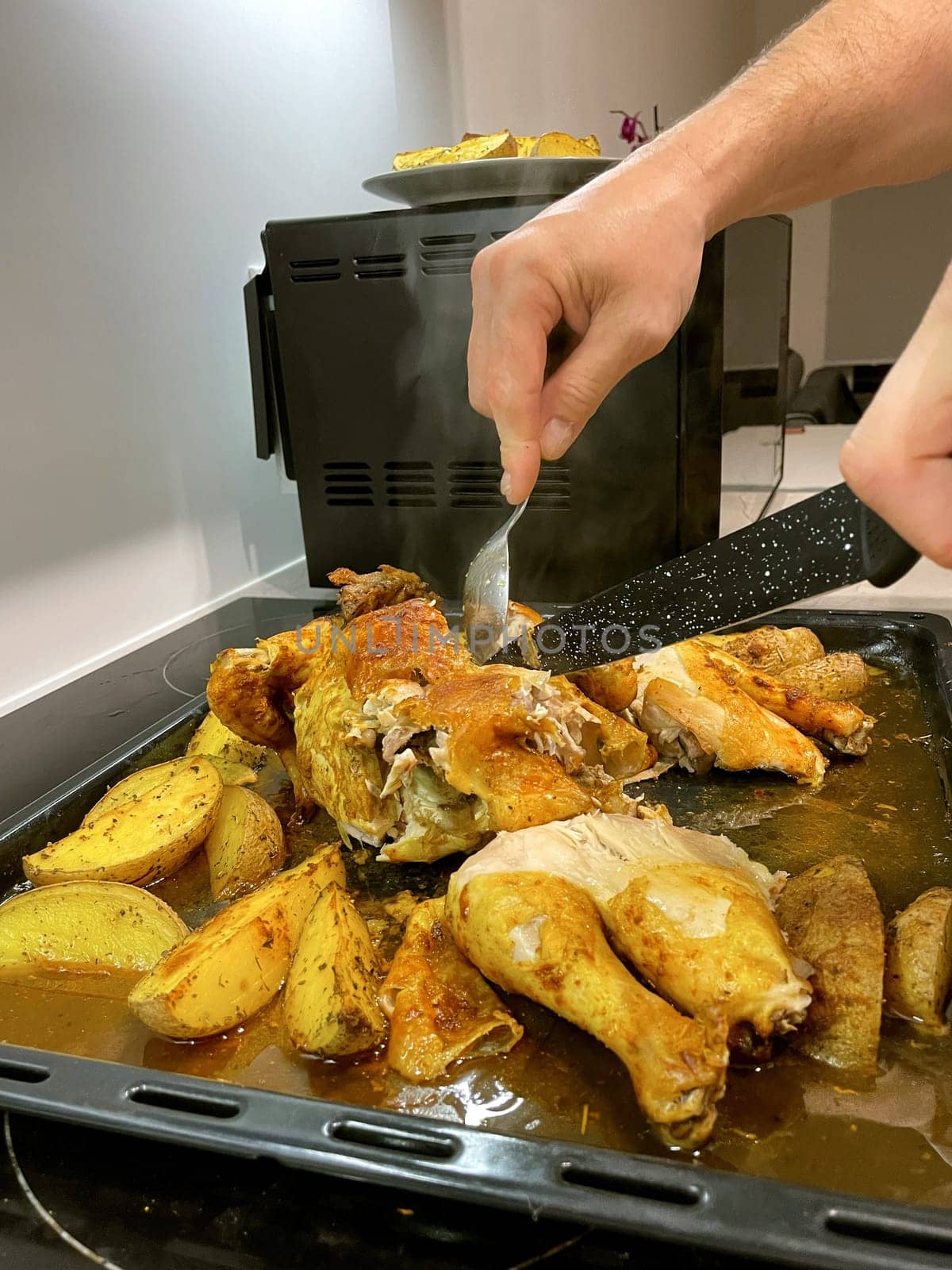 Hands cut baked chicken with potatoes with a knife. High quality photo