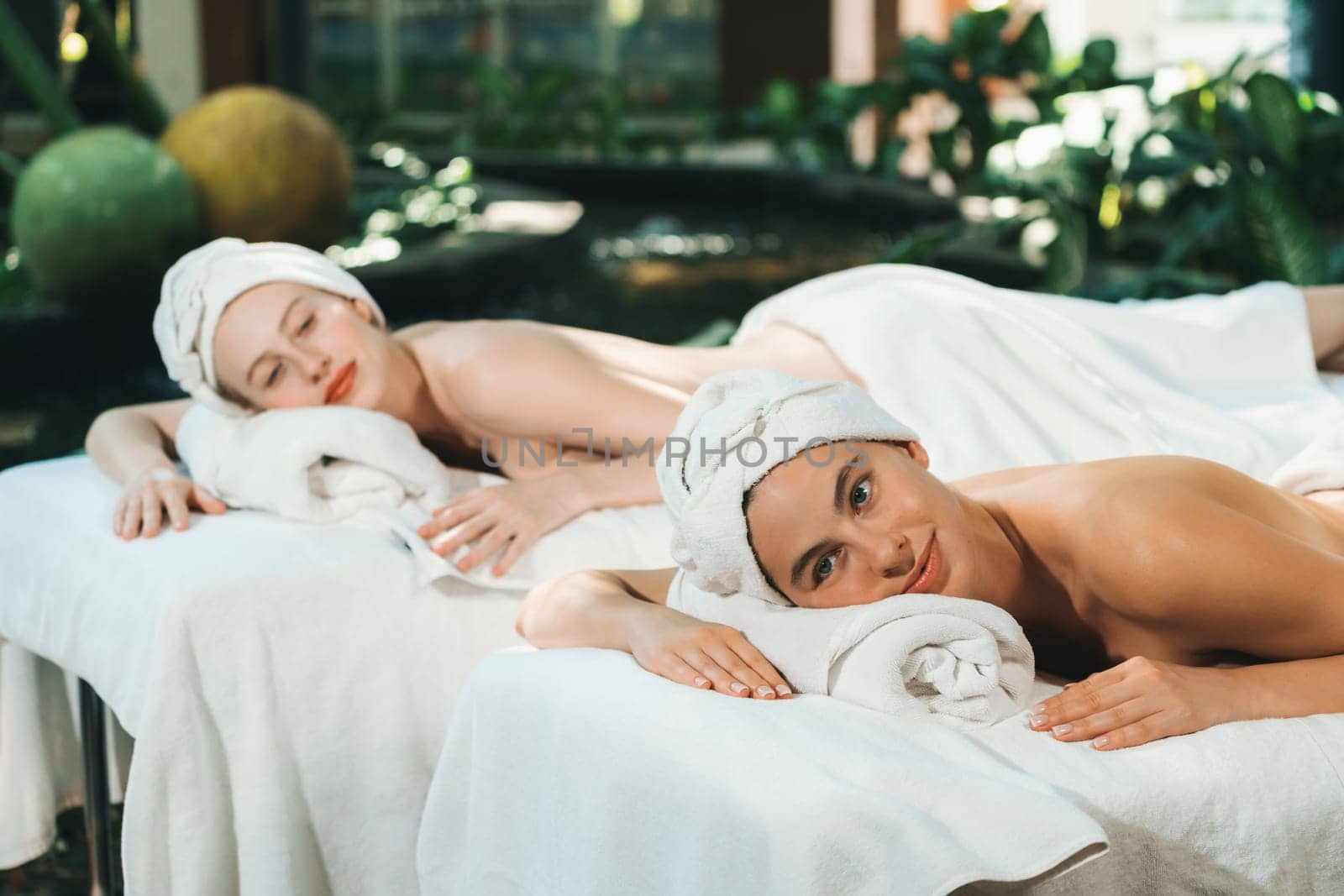 A portrait of a couple of attractive young woman lie on spa bed. Tranquility. by biancoblue