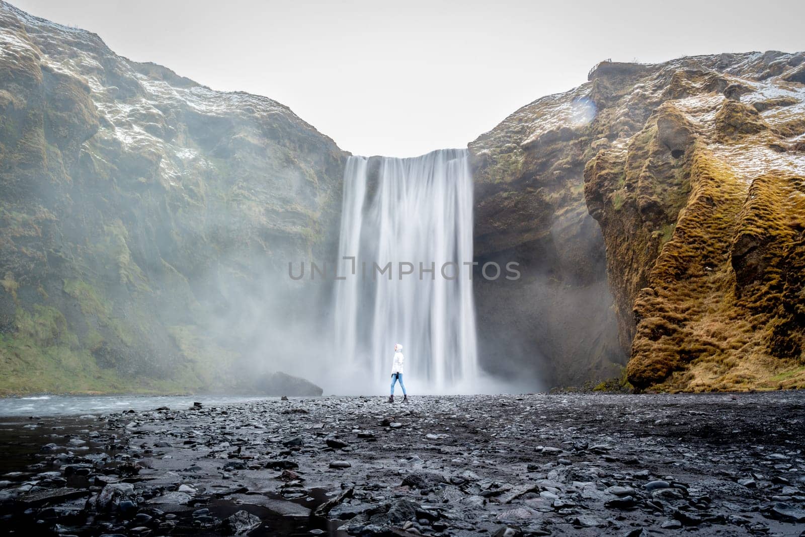 Unknown woman with white jacket from behind in Skogafoss, Iceland