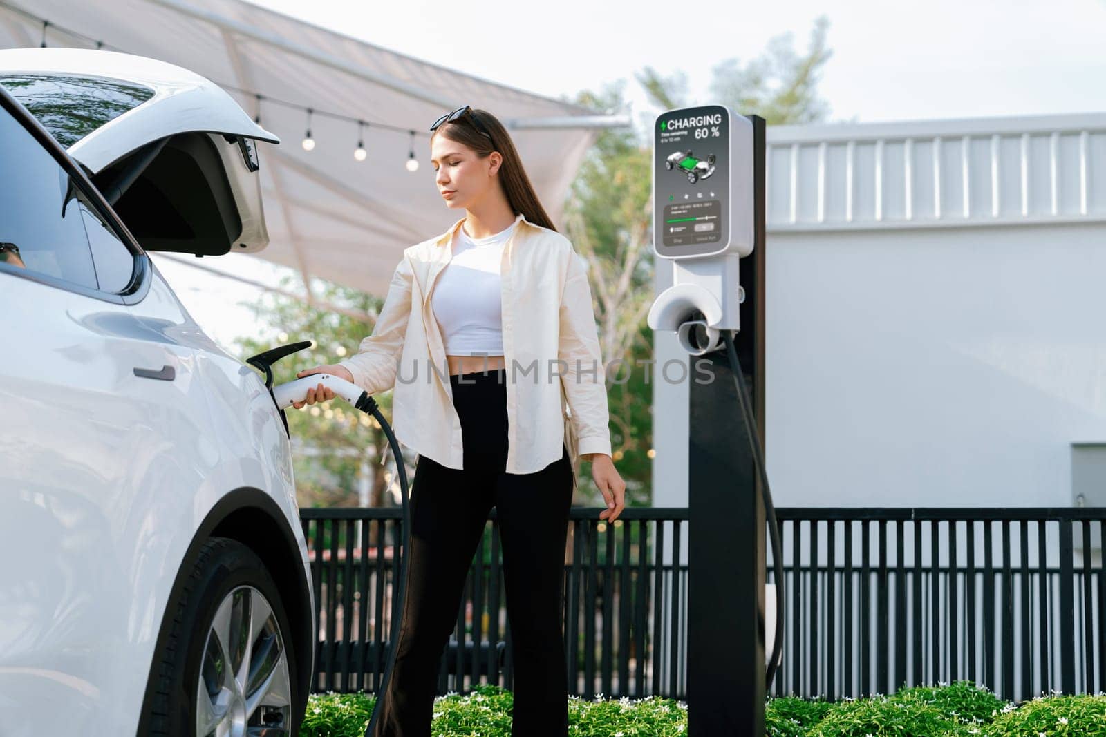 Young woman put EV charger to recharge electric car battery. Expedient by biancoblue