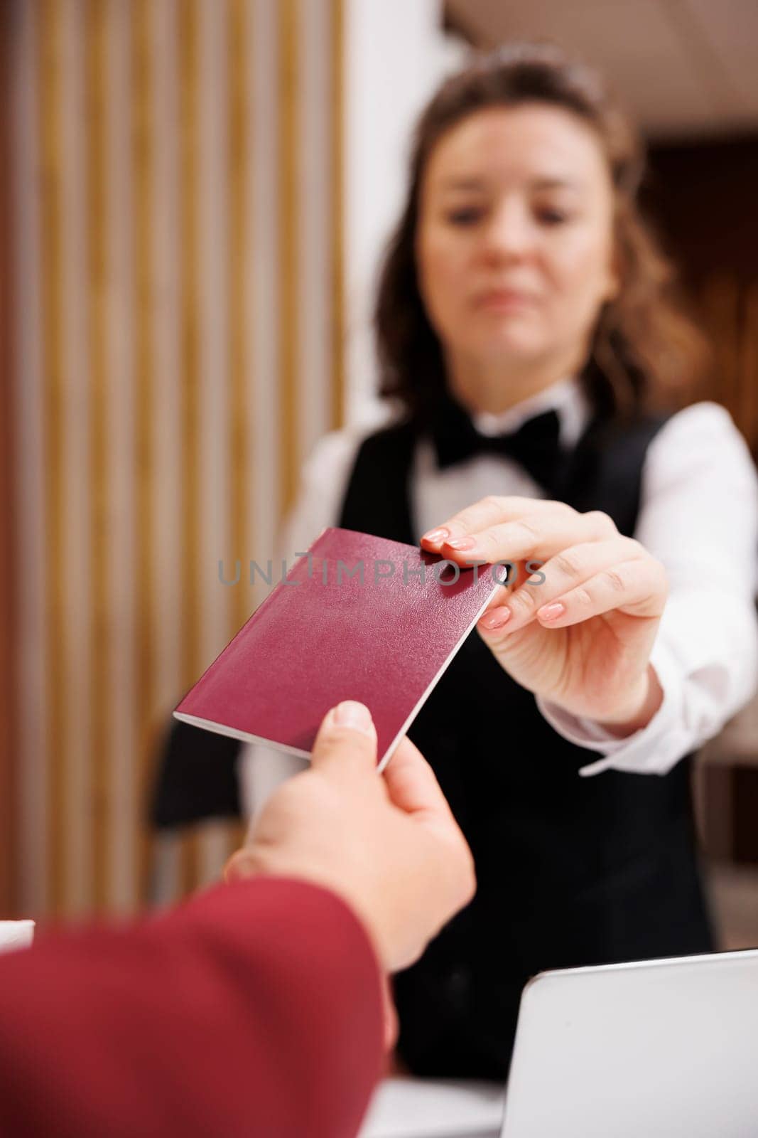Hotel concierge checks passport, taking identification files from guest to fill in papers and help him settle in. Businessman in suit travelling for corporate work trip. Close up.