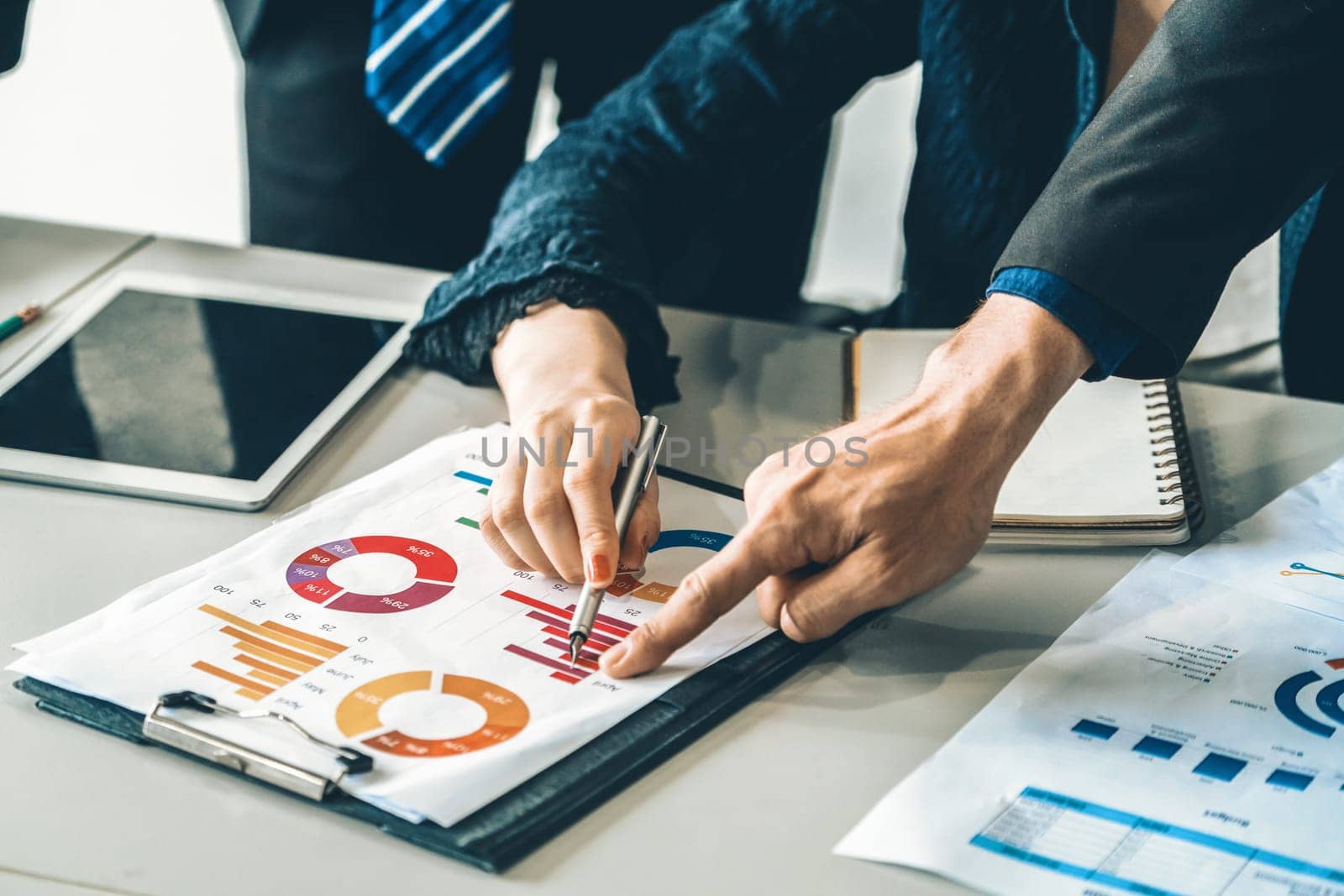 Businessman and businesswoman in meeting working with many financial statement document on desk. Concept of busy business profit analysis and brainstorm. Close up shot at people hands and papers. uds