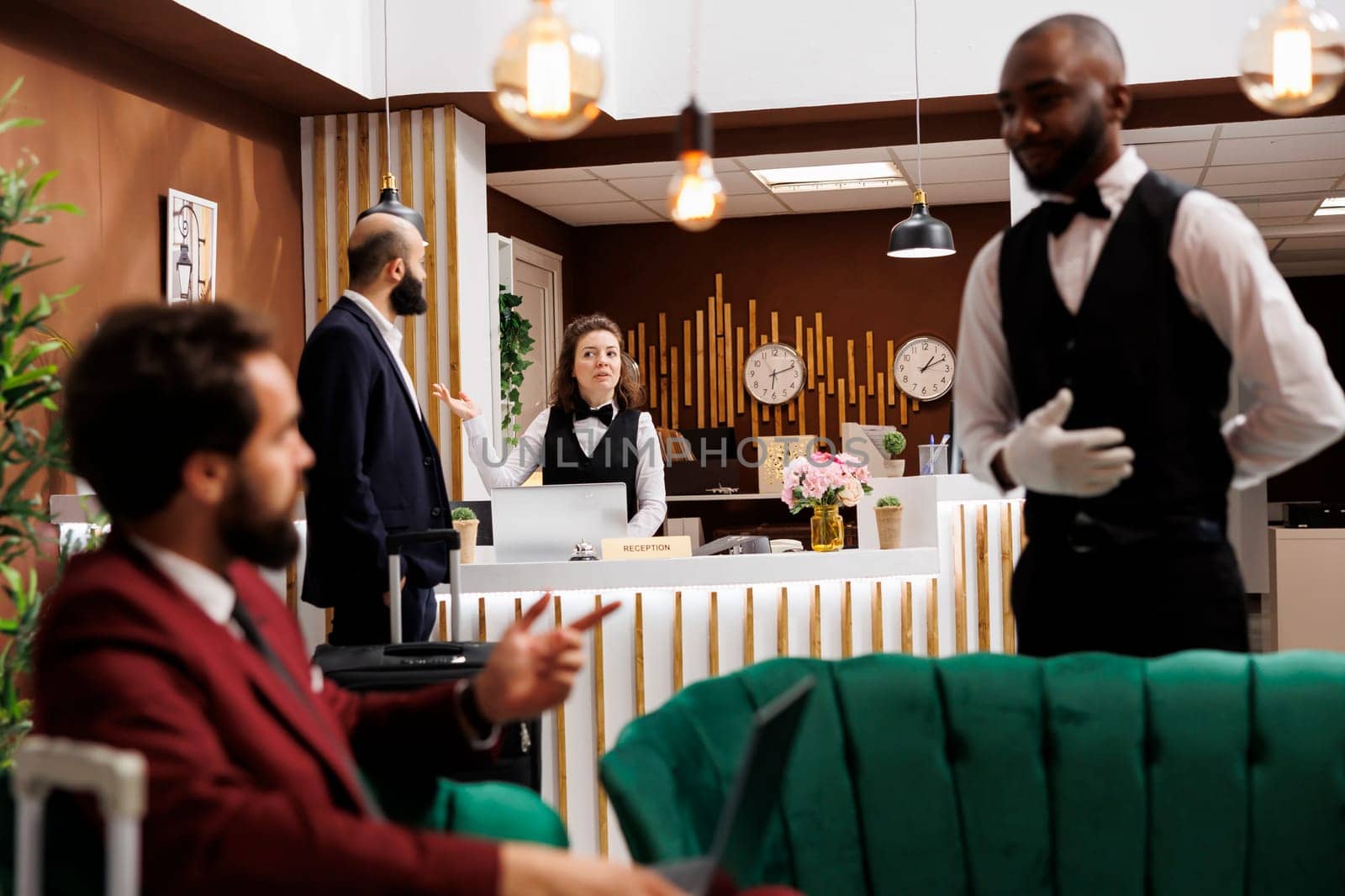 Front desk staff welcoming traveller, ensuring pleasant stay and check in process for businessman. Young man in suit attending partnership conferences abroad, registration at hotel.