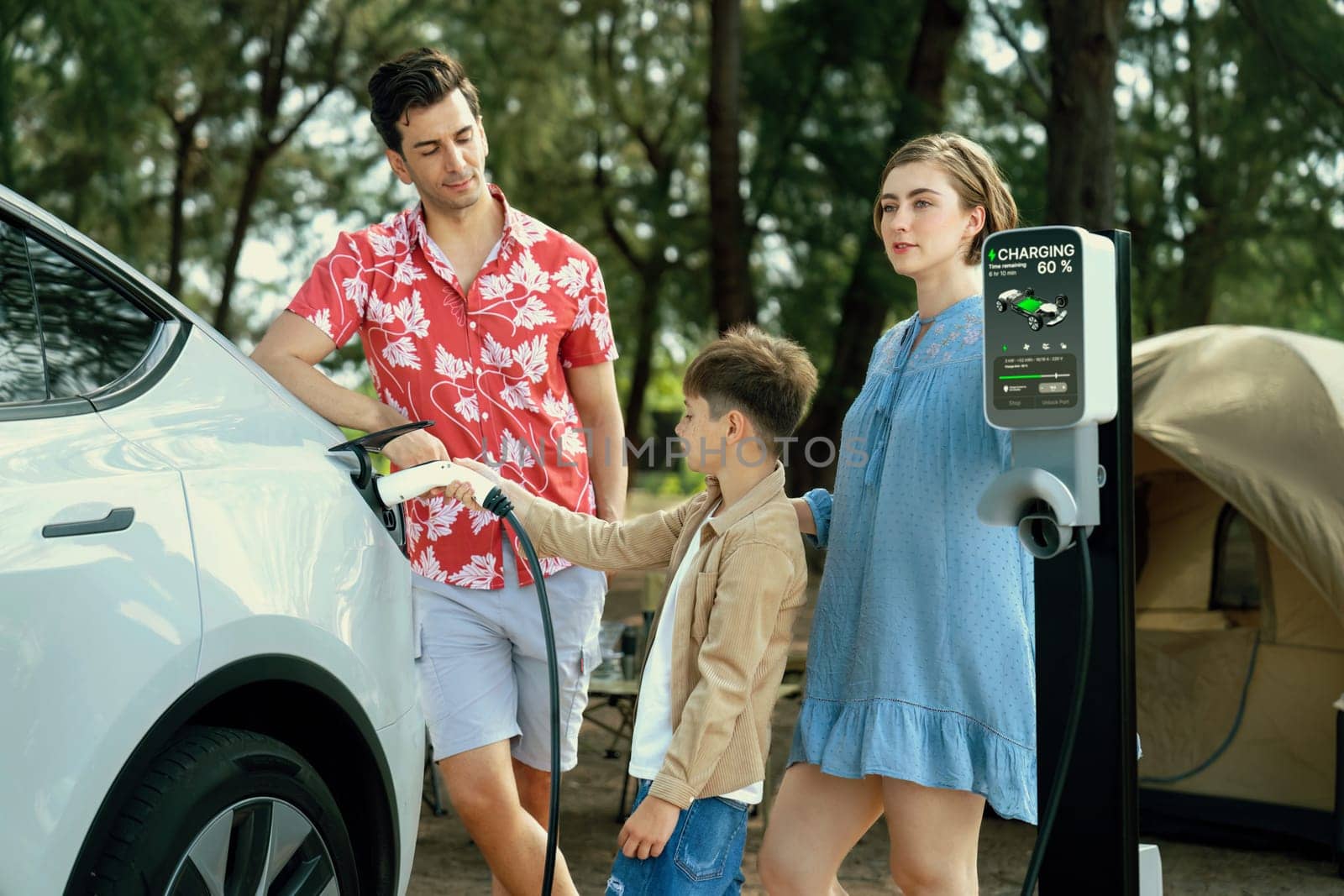 Outdoor adventure and family vacation camping in nature travel by eco friendly car for sustainable future. Lovely family recharge EV car with EV charging station in campsite. Perpetual