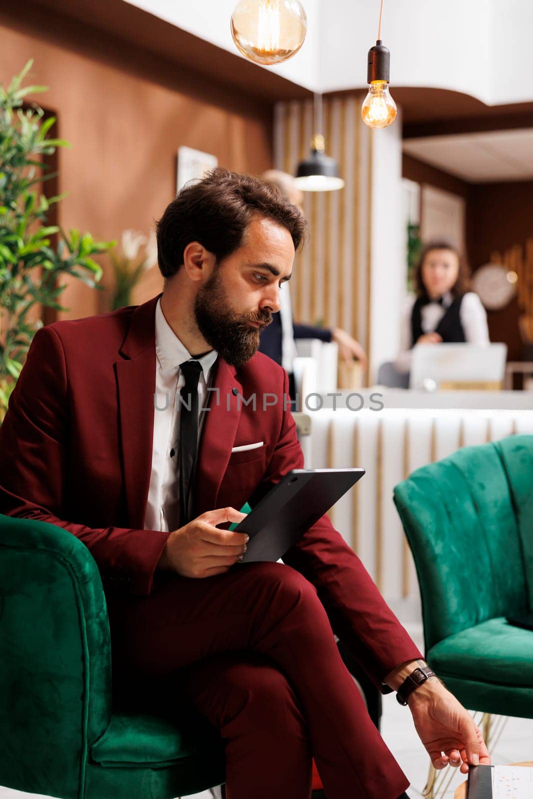 White collar worker checking files on tablet, working while he waits to do check in process at hotel. Businessman review notes before attending important meeting, business trip.