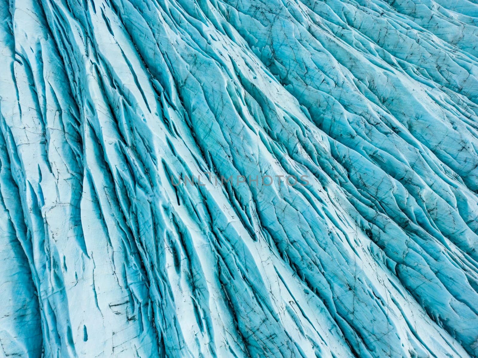 Aerial view of blue ice glaciers with crevasses, vatnajokull ice mass and glacier lagoon with freezing cold water in iceland. Diamond blue icy rocks surrounding scandinavian lake, climate change.