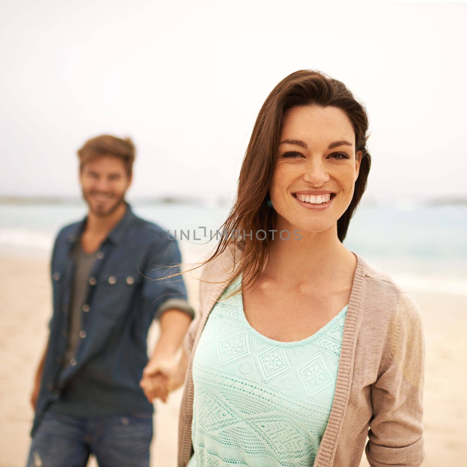 Portrait, smile and couple on walk in beach to relax in tropical vacation, outdoor and sunshine. Partners, happy and holding hands by sea with water on date for holiday, anniversary and love.