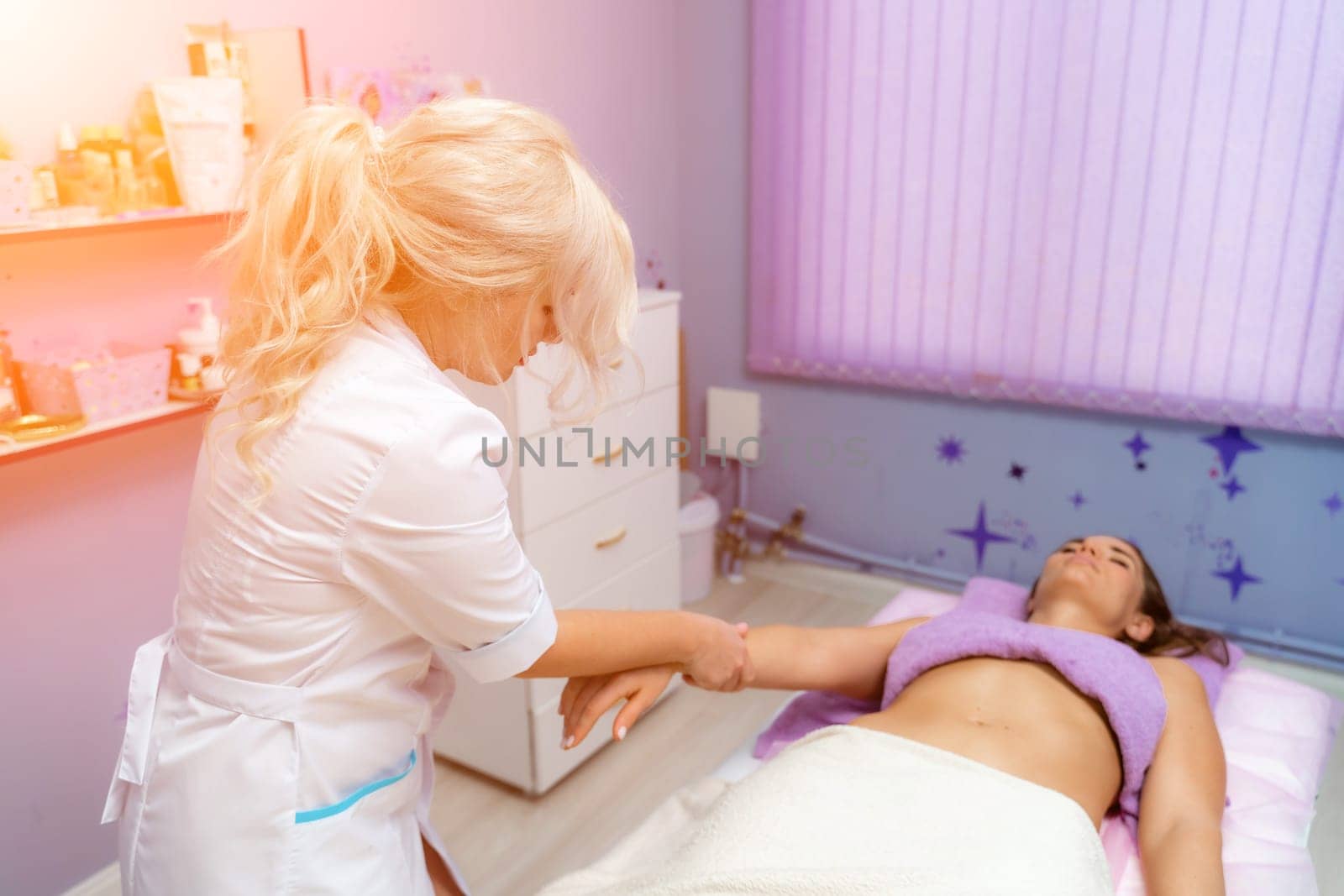 Blonde massage therapist massaging a woman. Woman getting a massage at the spa by Matiunina