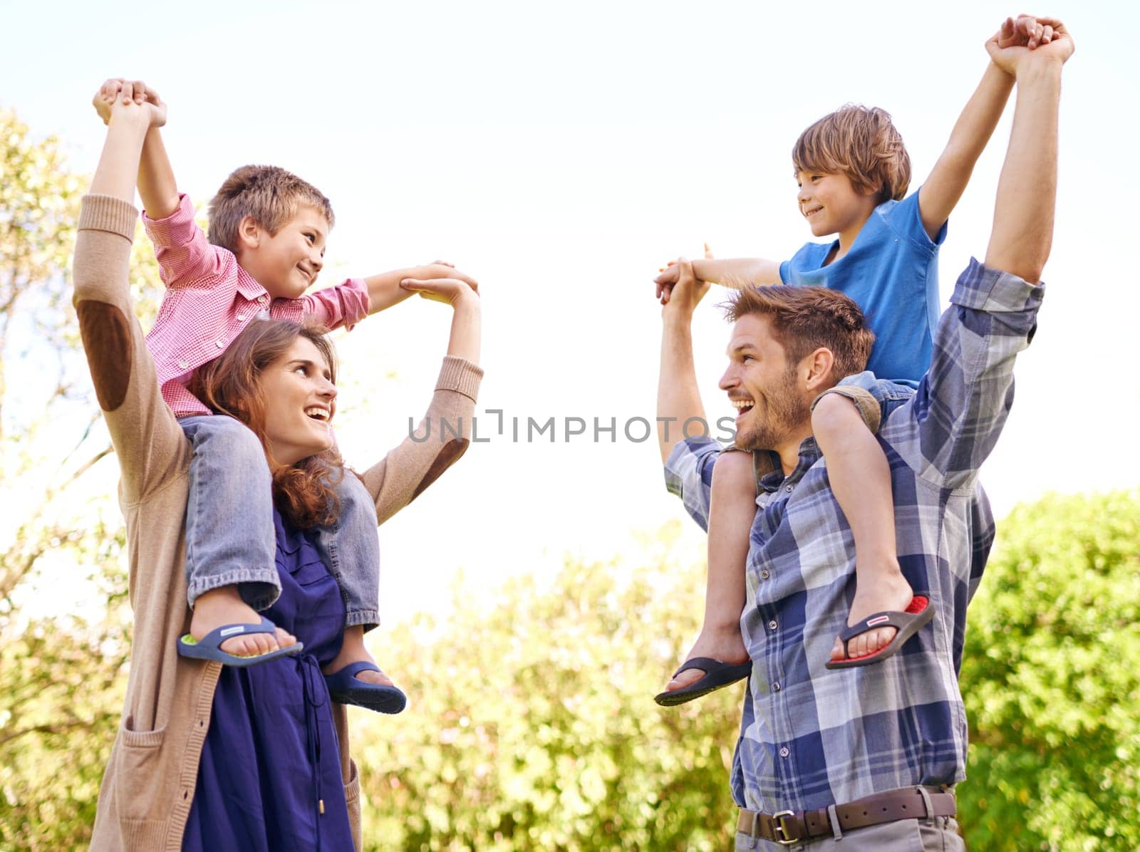 Smile, nature and kids on parents shoulders in outdoor park or field for playing together. Happy, bonding and young mother and father carrying boy kids for fun in garden in Canada for summer