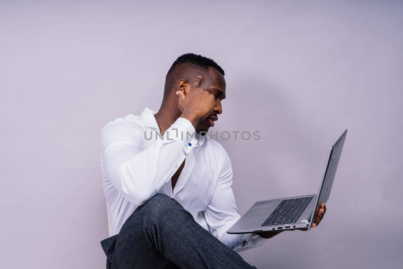 Young cheerful happy man of African American ethnicity laptop pc computer studio portrait. by Zelenin