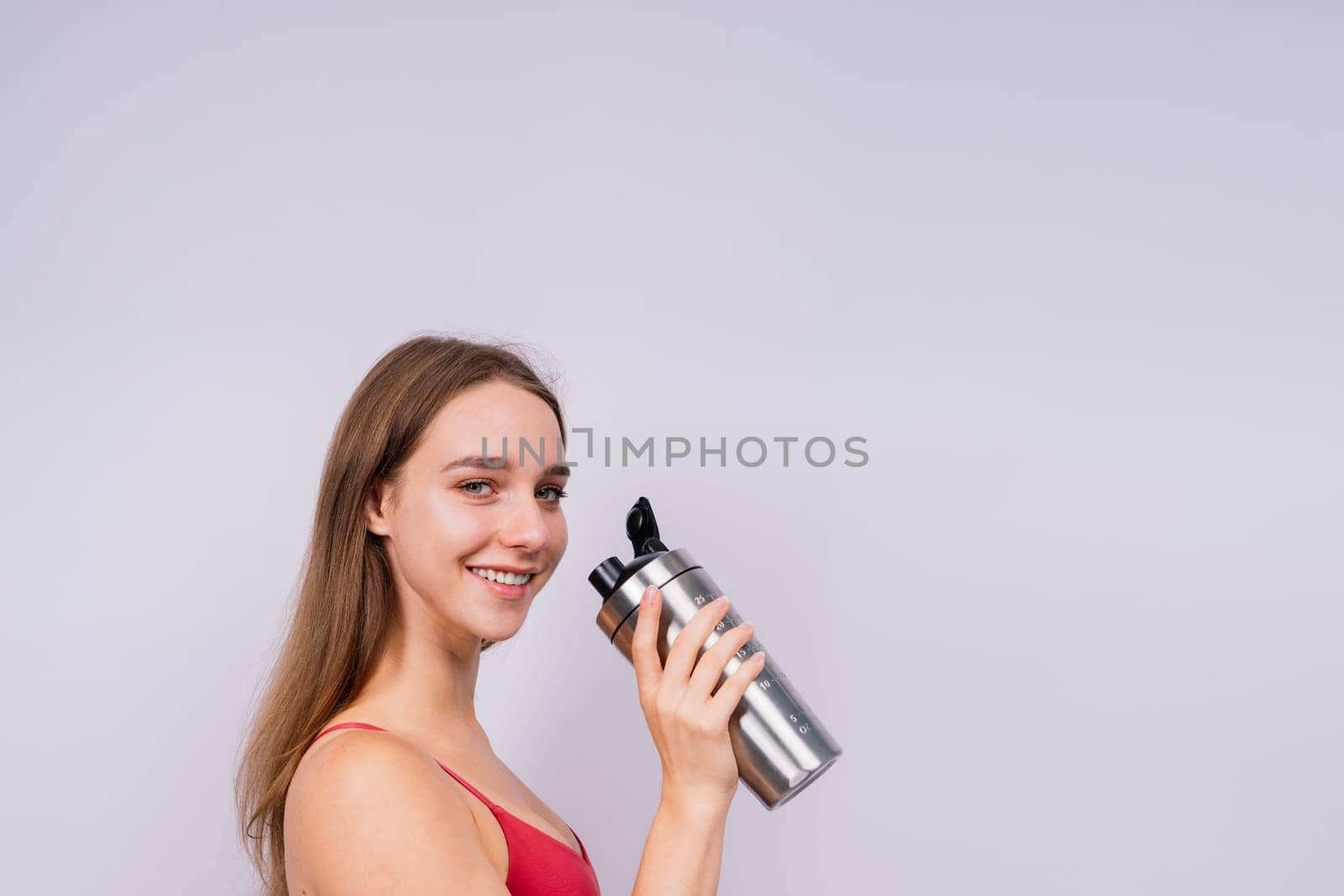 Image of beautiful strong happy cheerful young sports woman posing isolated indoors drinking water. by Zelenin