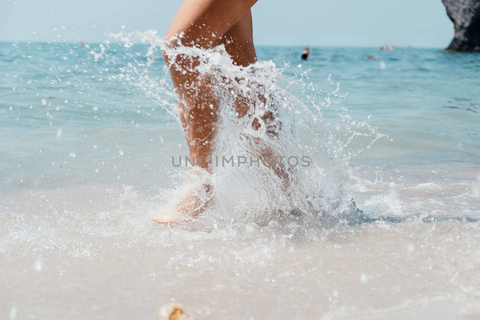 Sea beach travel - woman walking on sand beach leaving footprints in the white sand. Female legs walking along the seaside barefoot, close-up of the tanned legs of a girl coming out of the water