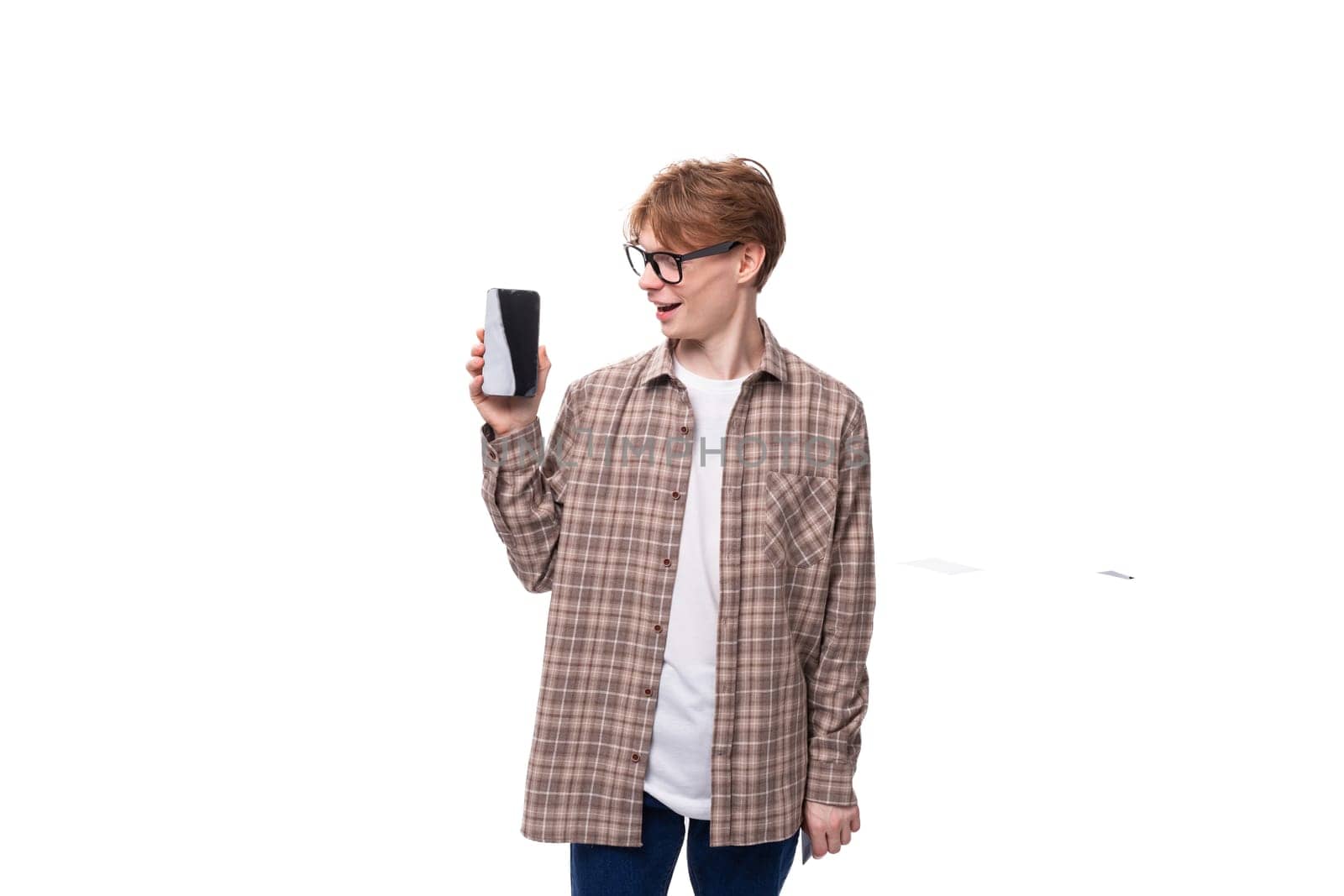 of a cute caucasian student guy in glasses shows the screen of a mobile phone. advertising concept by TRMK