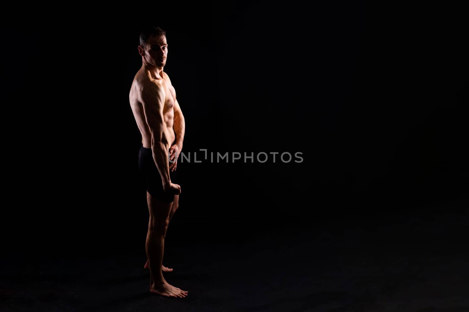 Image of muscle man posing in studio, dark white red background by Zelenin