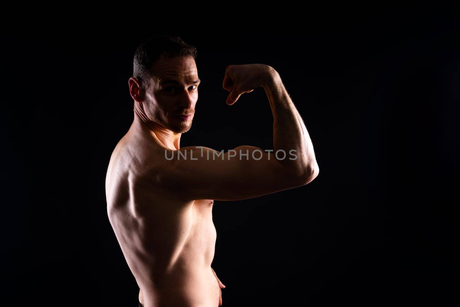 Image of muscle man posing in studio, dark white red background by Zelenin