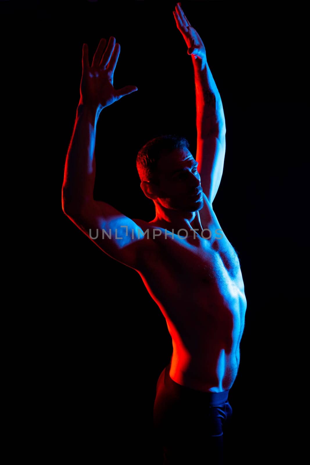 Image of muscle man posing in a studio, dark white red background