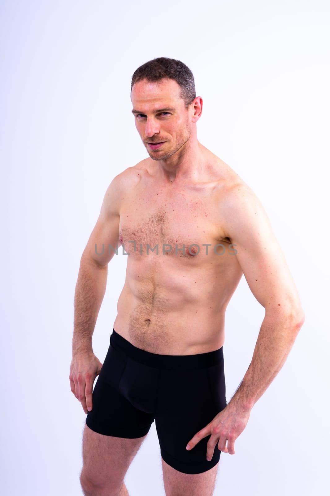 Image of muscle man posing in a studio, dark white red background