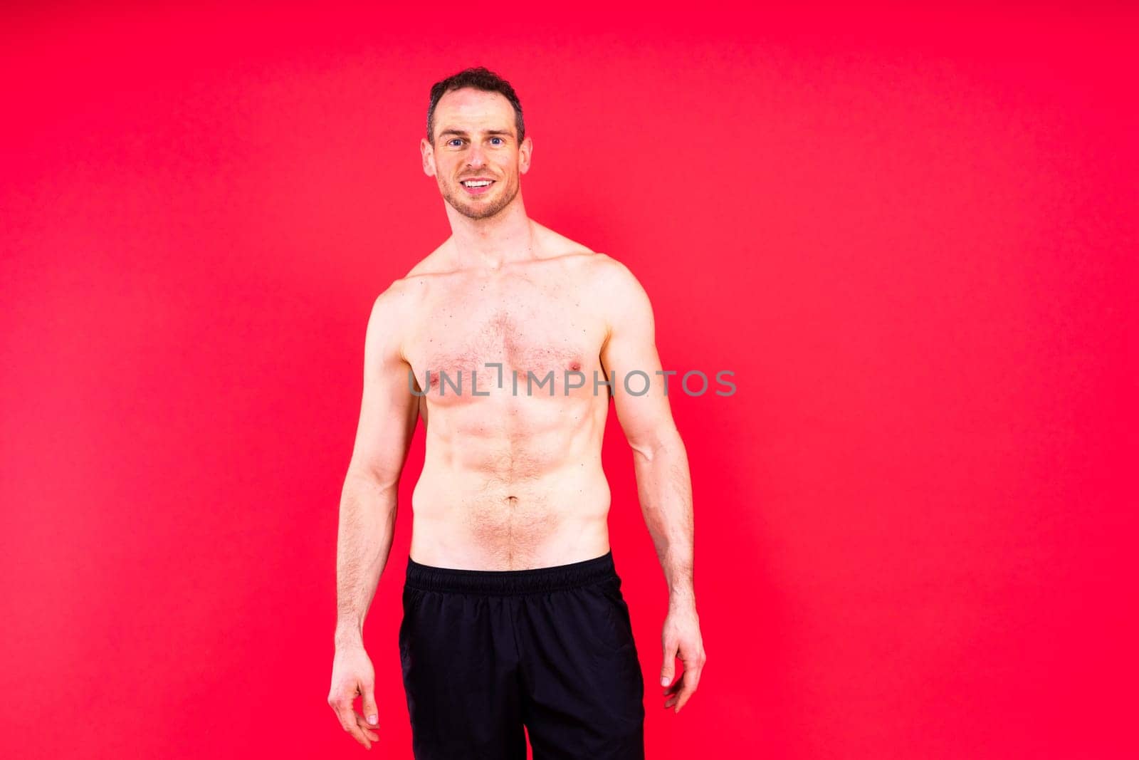 Image of muscle man posing in studio, dark white red background by Zelenin