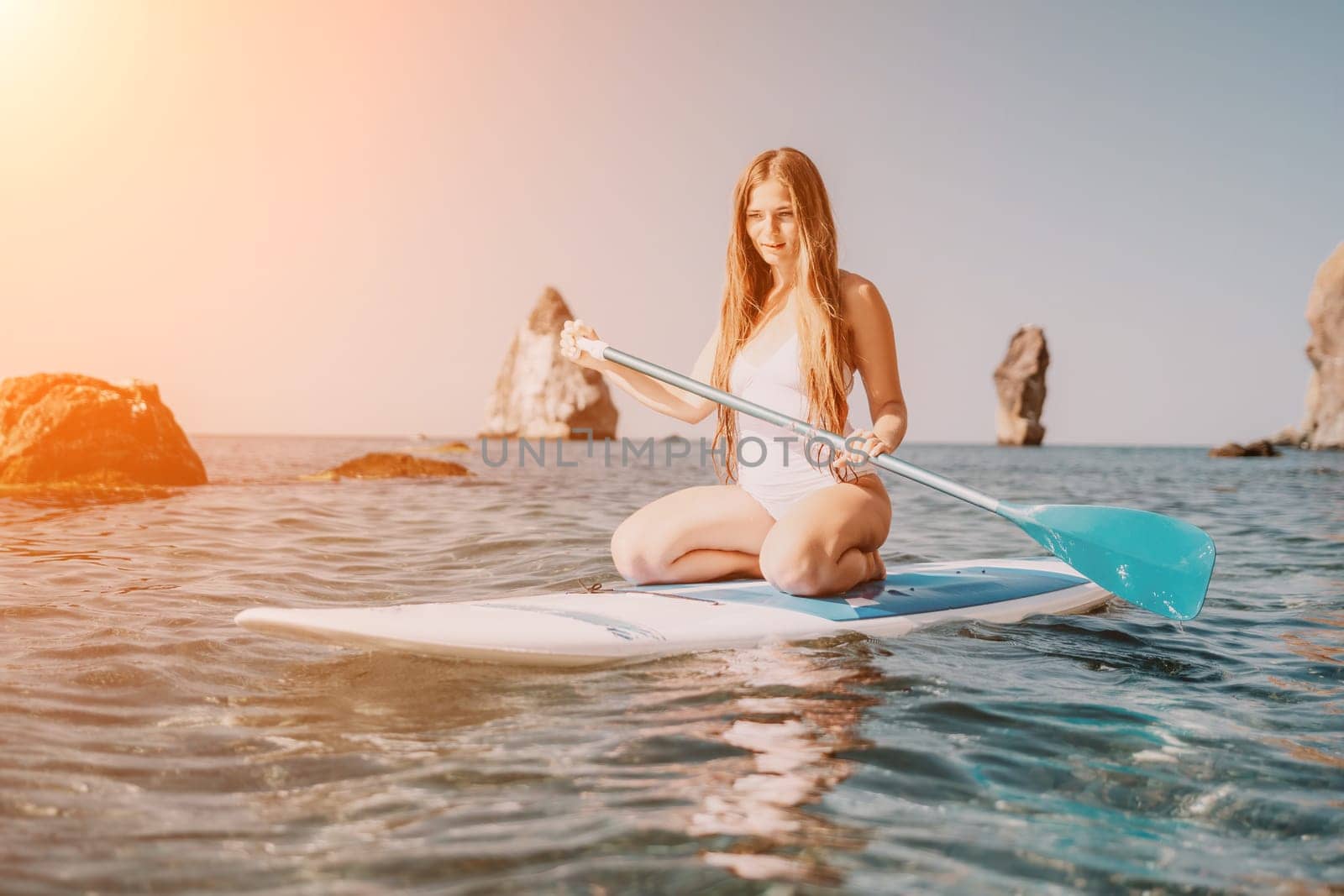 Close up shot of happy young caucasian woman looking at camera and smiling. Cute woman portrait in bikini posing on a volcanic rock high above the sea