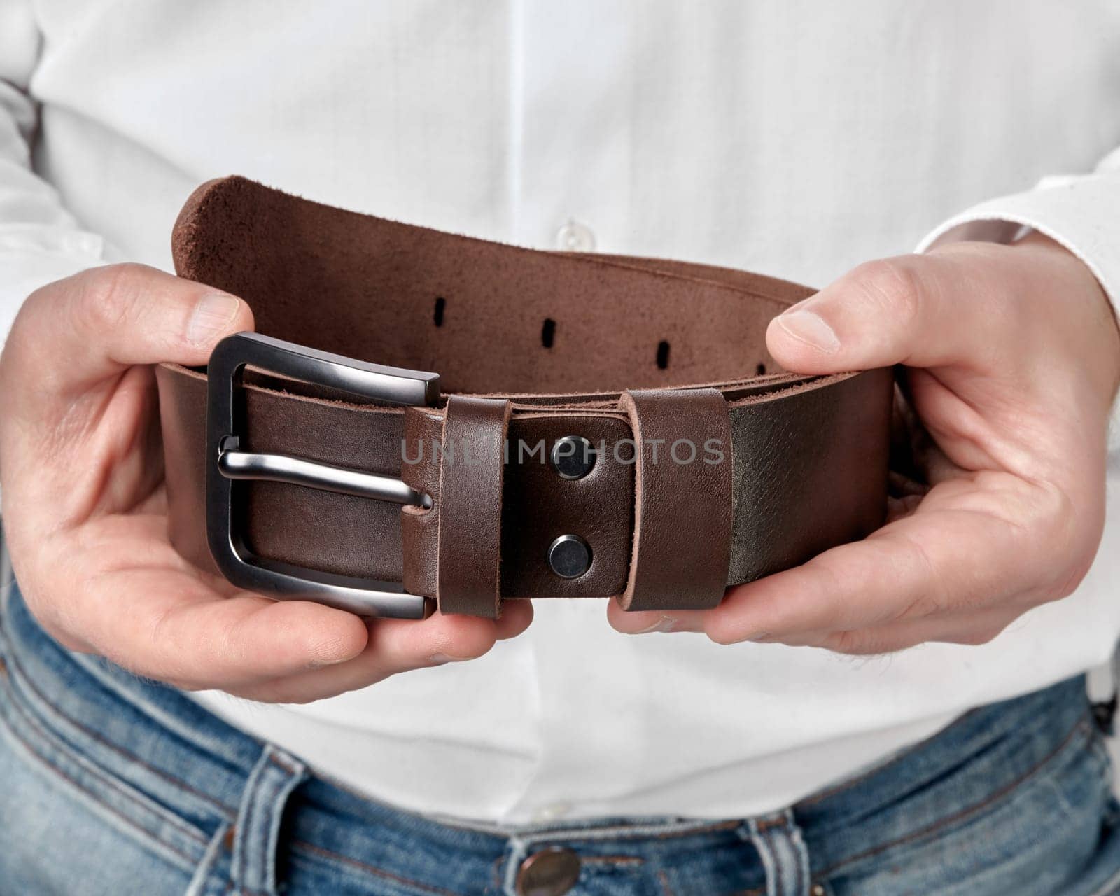 Closeup of stylish handcrafted dark brown genuine leather belt with DAD embossing in male hands, combining individual style with artisanal quality