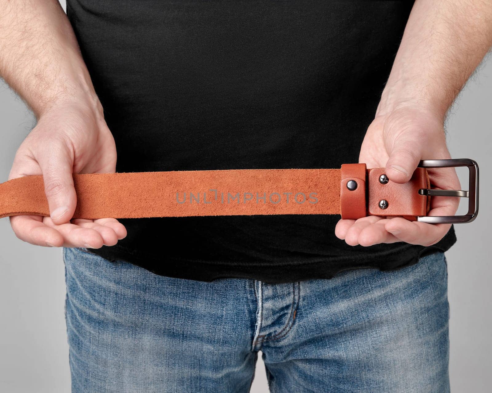 Man presenting terracotta genuine leather belt featuring humorous personalized inscription, adding touch of personality to classic accessory, cropped shot