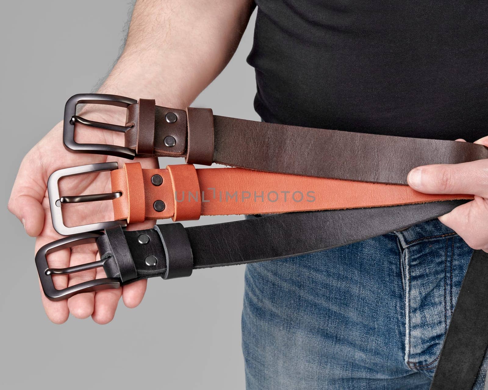 Leather belts of different colors with DAD embossings in male hands by nazarovsergey