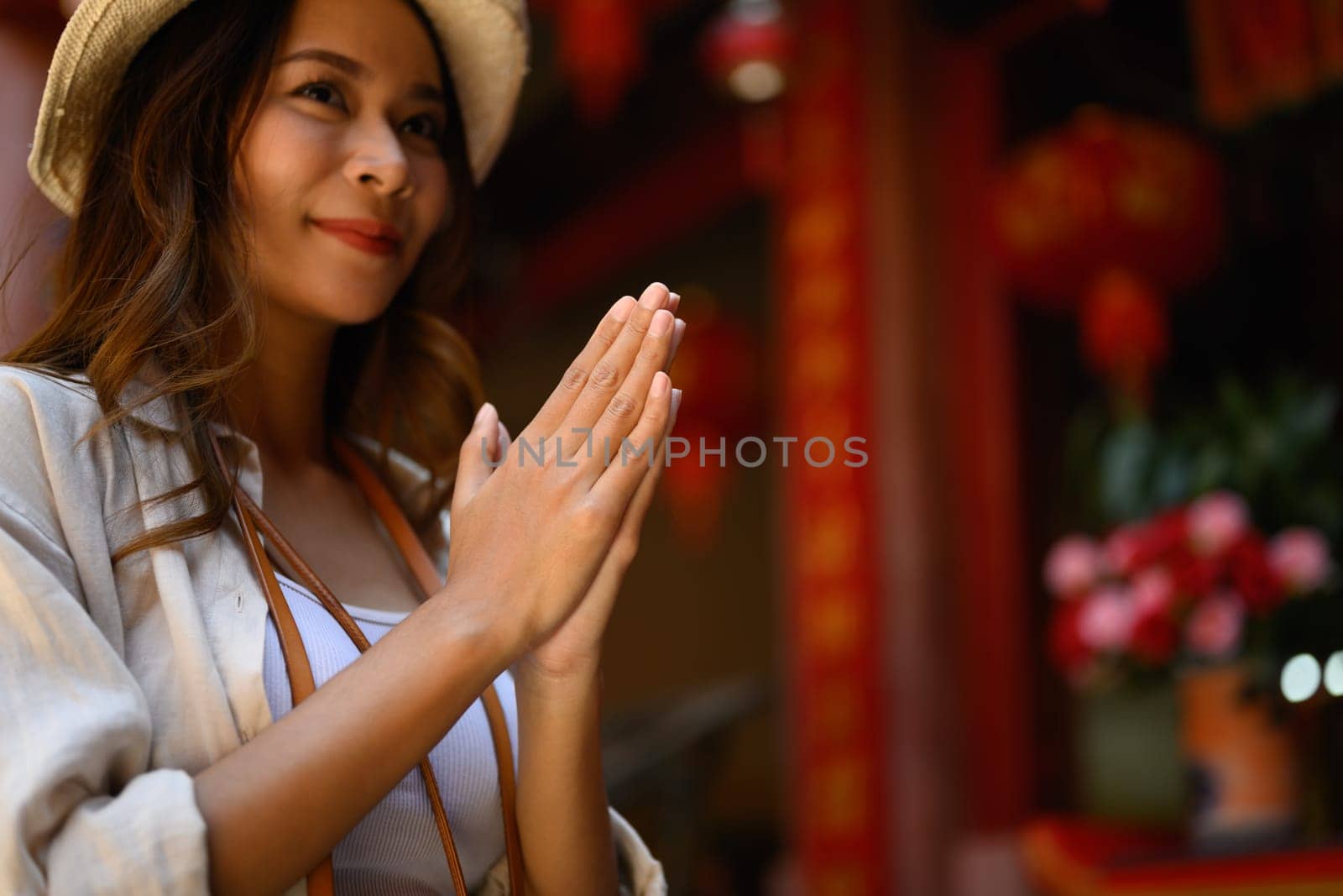 Attractive woman tourist praying to wish at Chinese Temple with beautiful red lanterns adorning.