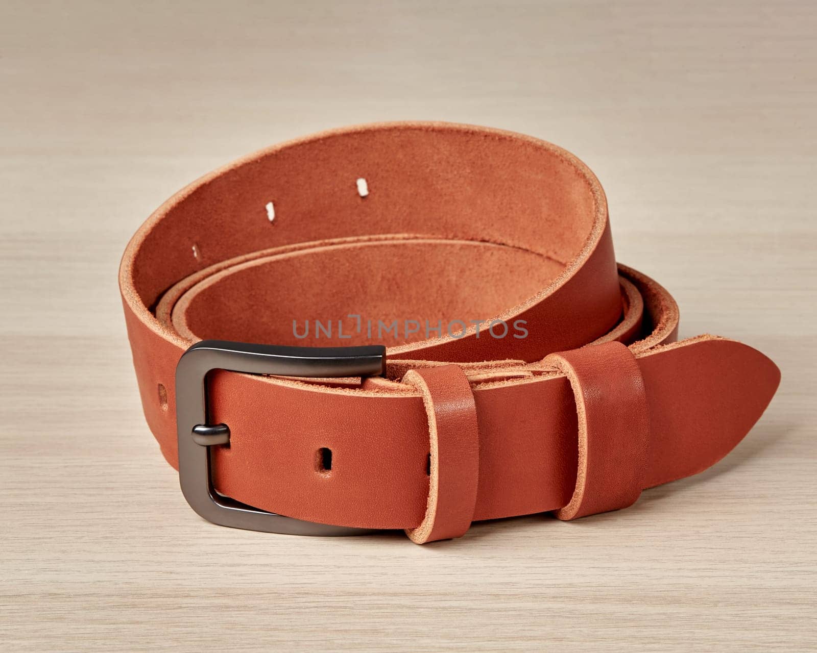 Folded on wooden surface, artisan terracotta leather belt with custom DAD inscription on loop, showcasing thoughtful blend of style and craftsmanship, ideal for gift for father