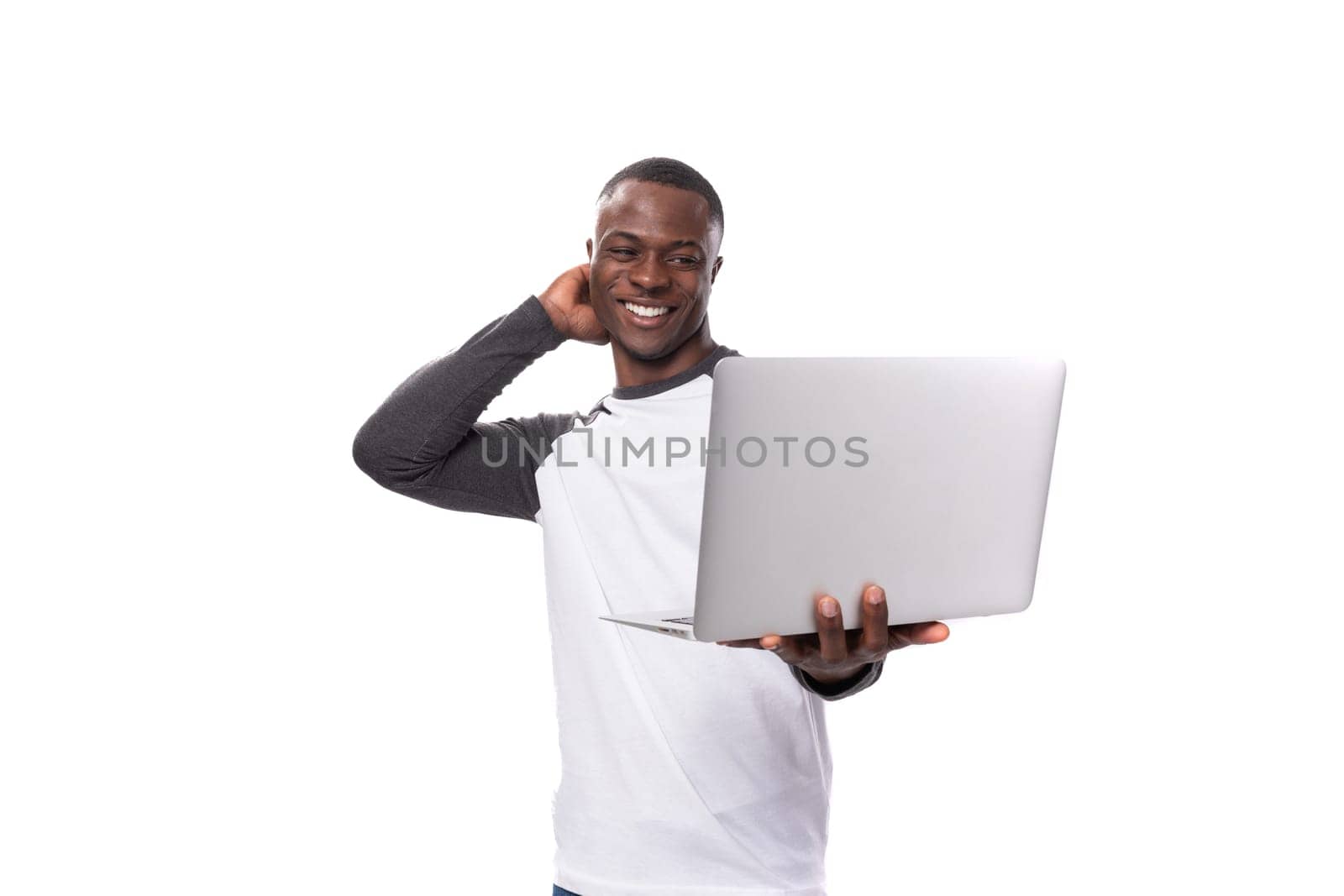 young african guy with short haircut is using laptop for remote work.