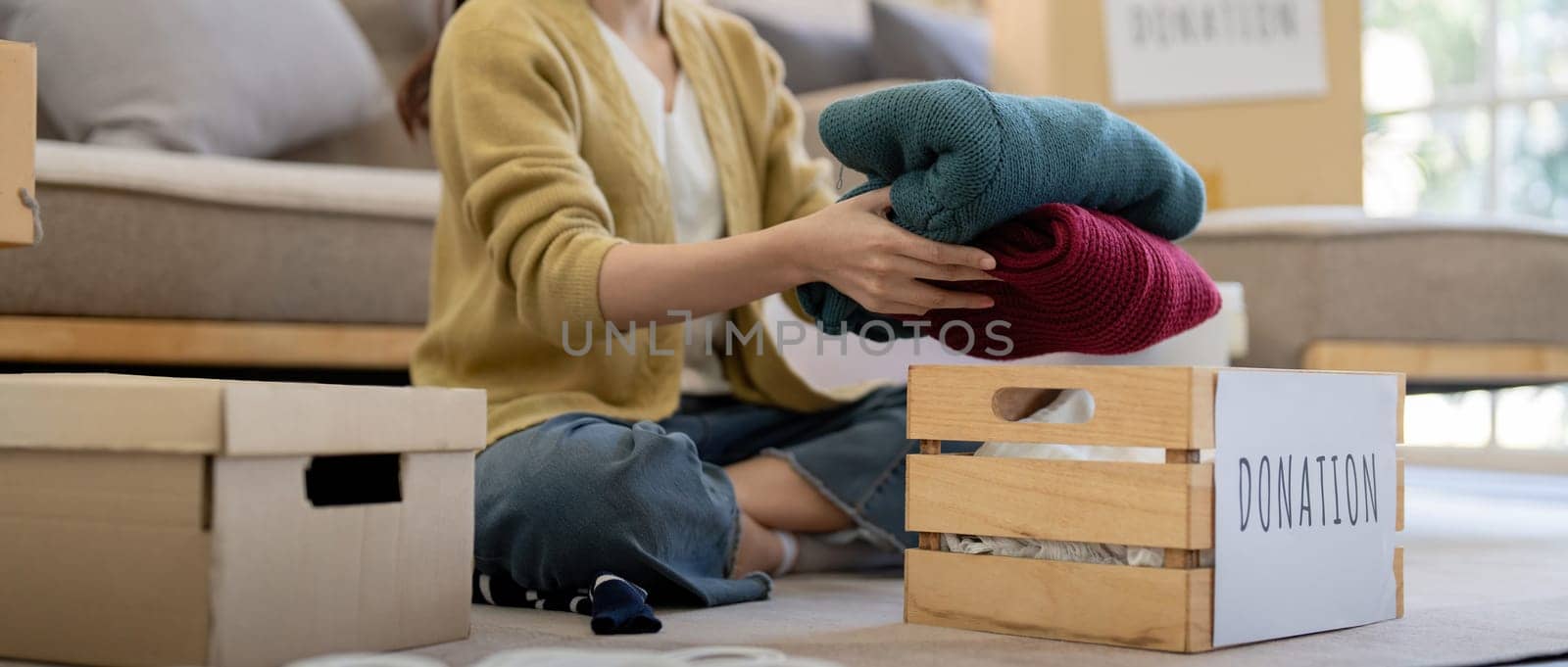 Donation, asian young woman sitting pack object at home, putting on stuff into donate box with second hand clothes, charity helping and needy people. Reuse recycle.