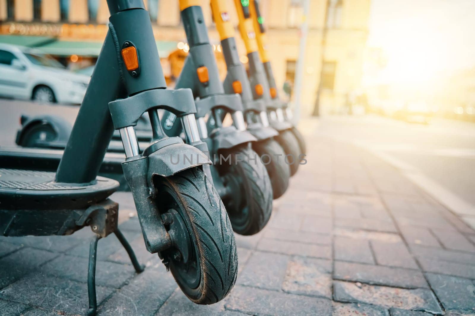 A line of motor vehicles with Automotive tires are parked on the sidewalk, their wheels made of synthetic rubber with treads. Some have bumpers and automotive lighting