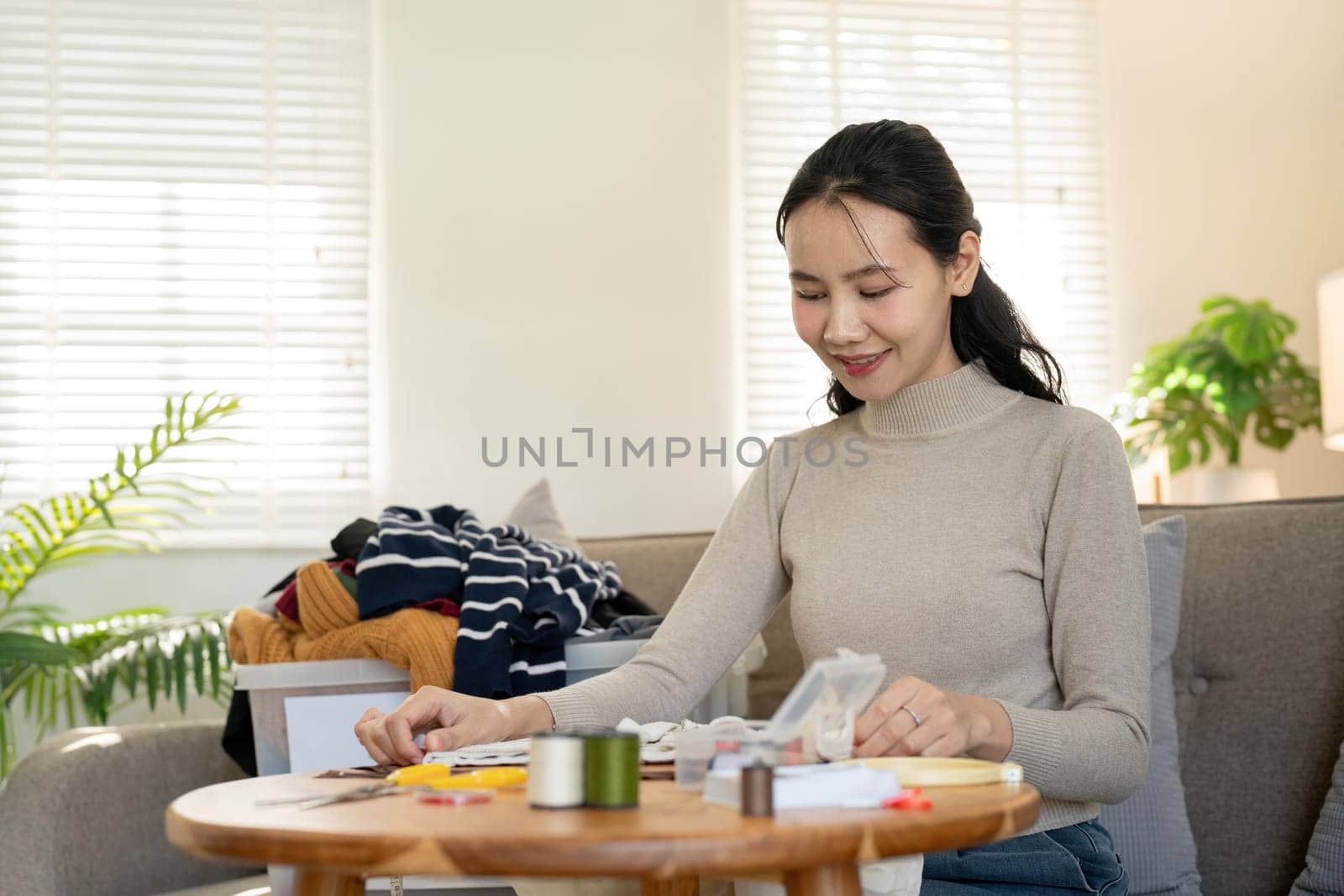 Woman repairs sews reuses fabric from old clothes economical reuse. DIY Hobby Reuse Recycling at home.